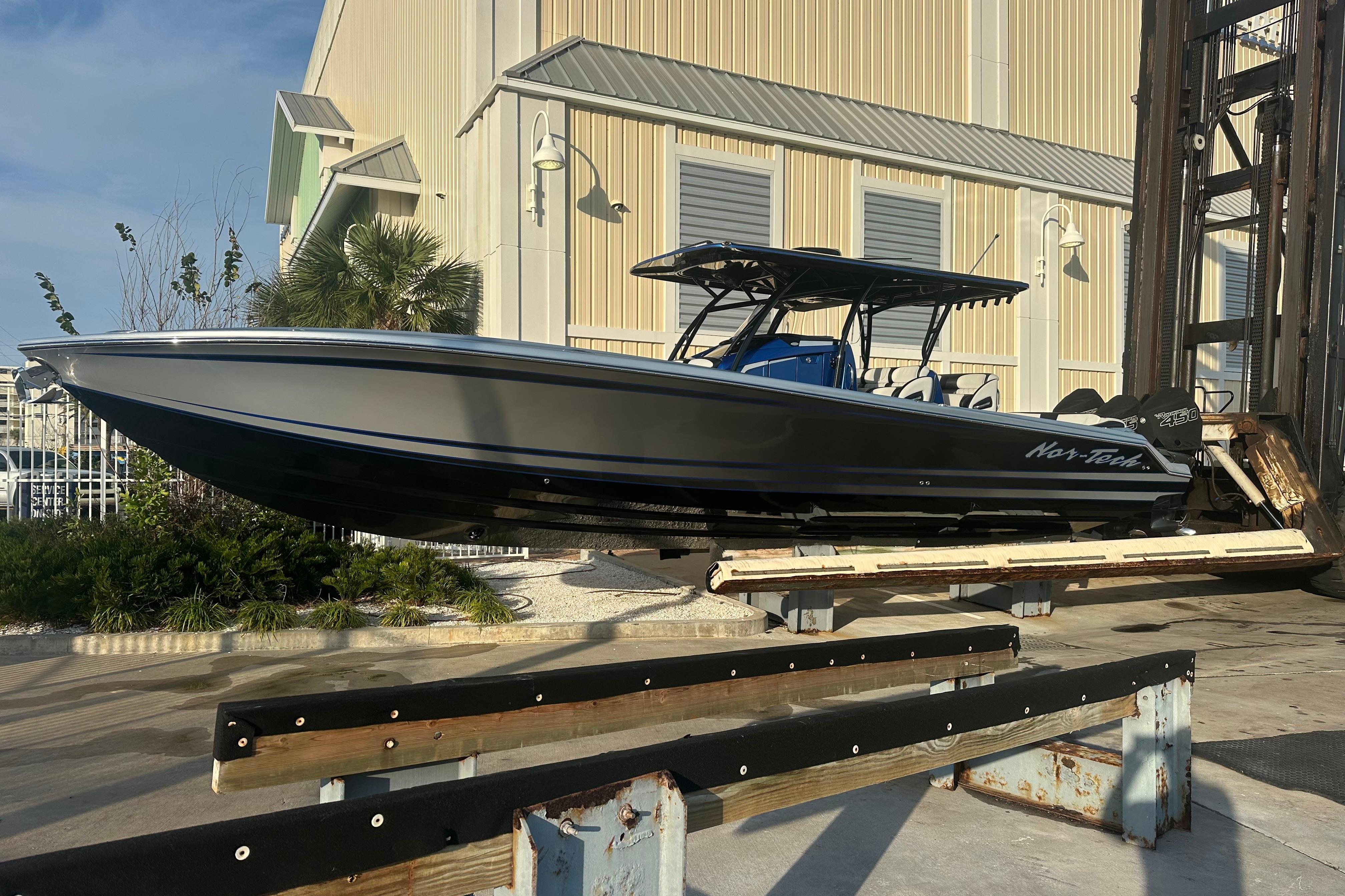 2022 Nor-Tech 390 Sport Center Console boat on lift, near industrial building.
