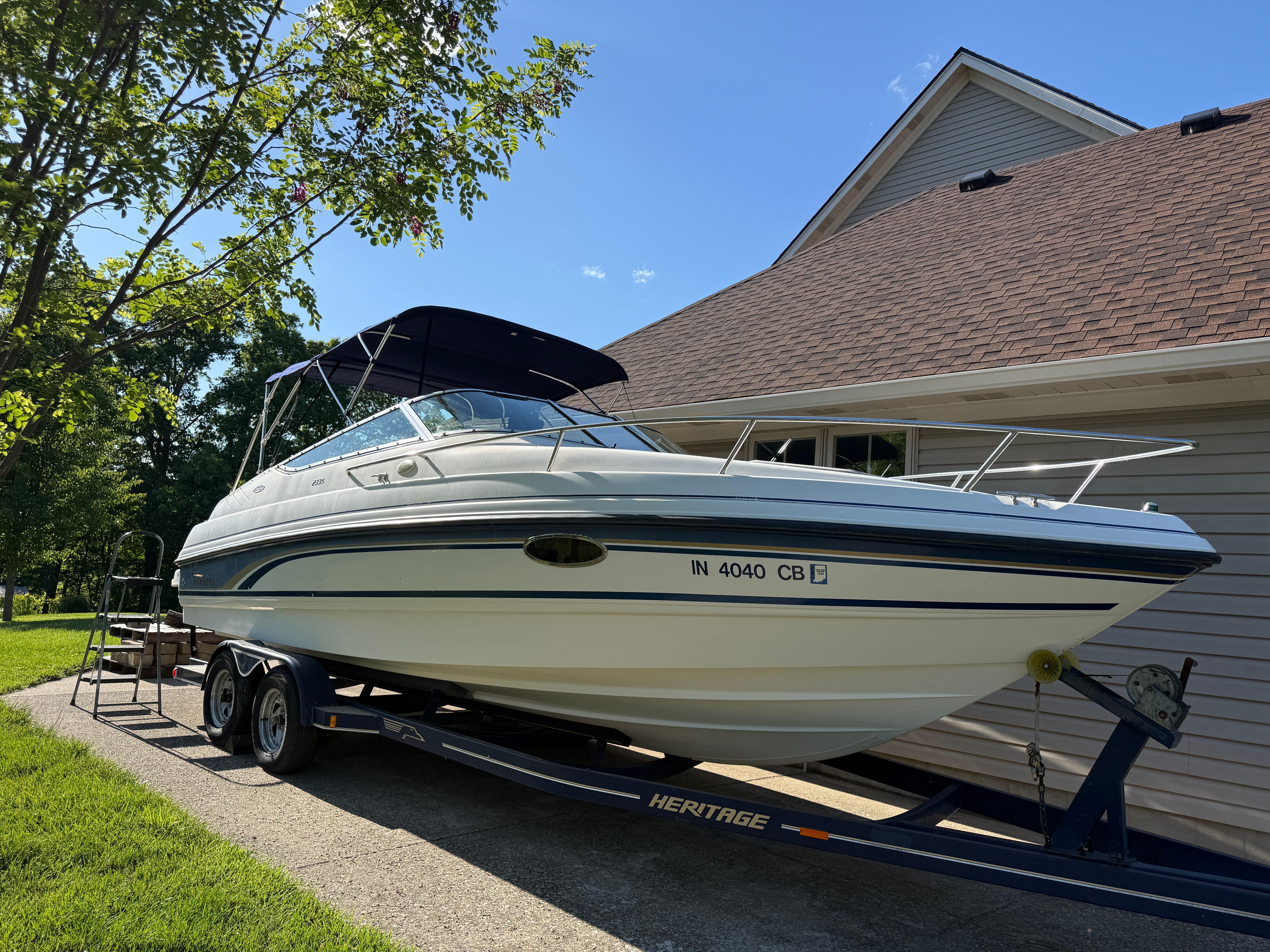 1999 Custom 2335 Cuddy Cabin boat on trailer beside house.