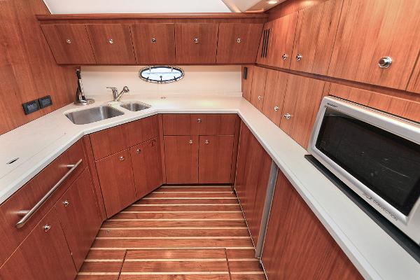 2008 Tiara Yachts 4200 Open kitchen with wood cabinetry, stainless steel sink, and microwave.