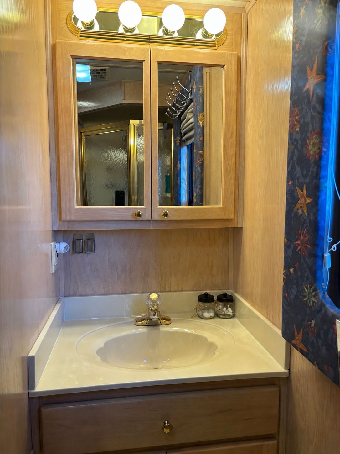 A stylish bathroom with wooden cabinets and a sink, illuminated by light bulbs.