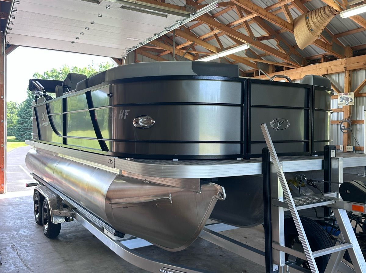 A 2022 Veranda Relax VR20RC pontoon boat is on a trailer in an open shed.