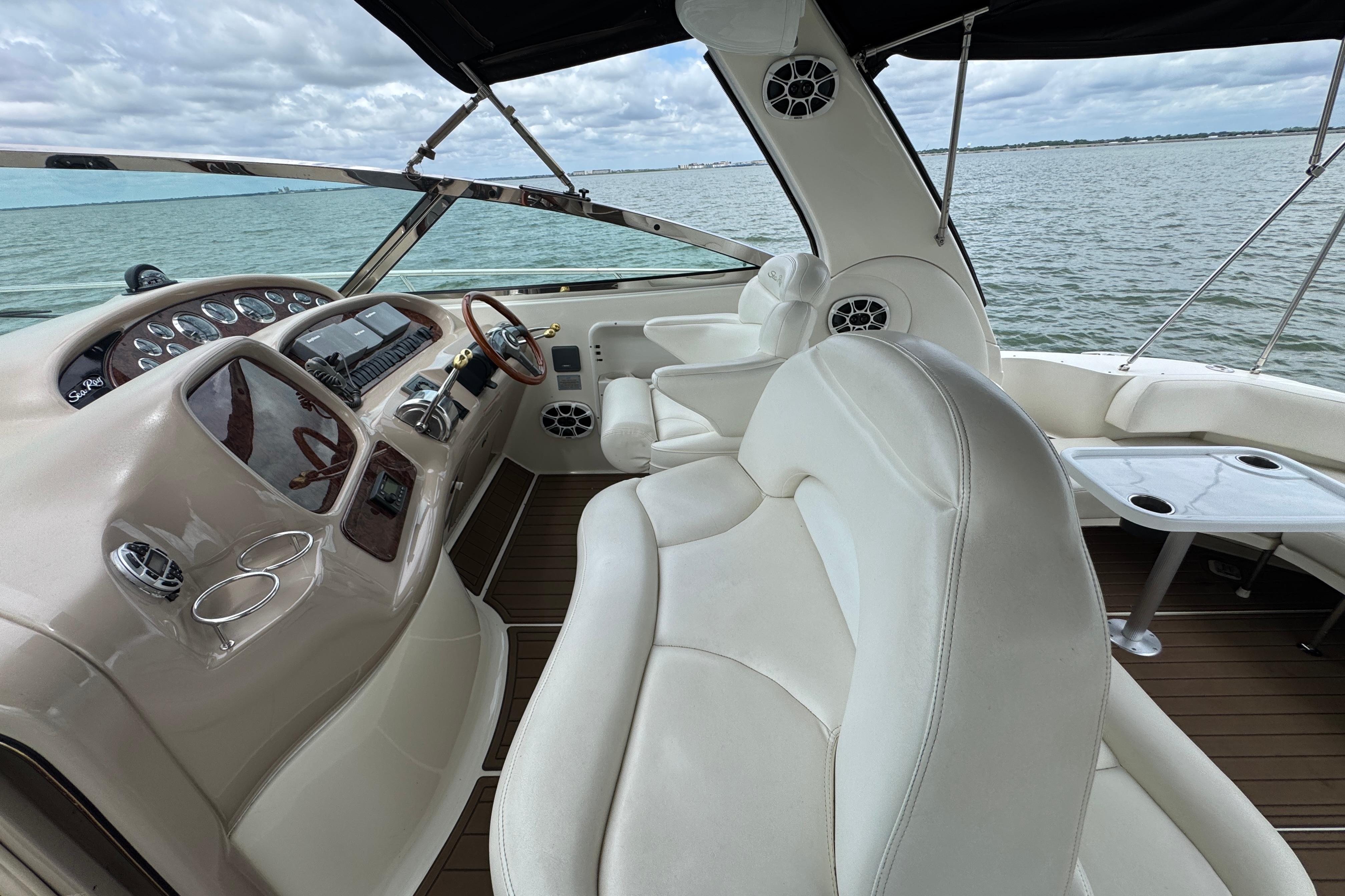 2001 Sea Ray 380 Sundancer cockpit with white seating and wooden accents, overlooking the water.