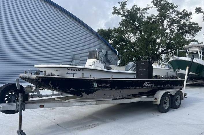2016 Pro-Drive X Series 20' boat on trailer, parked near blue building.