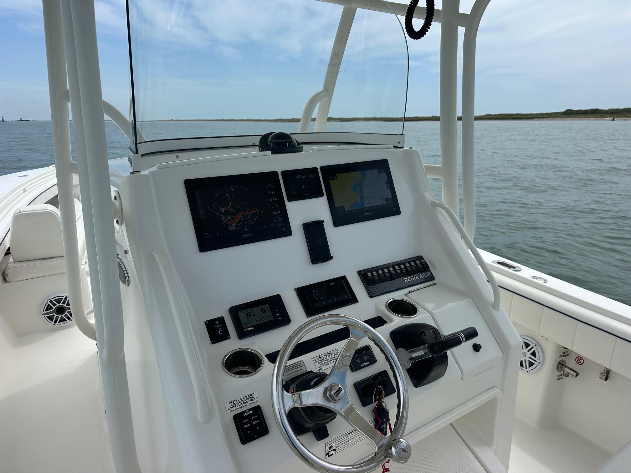 2016 Regulator center console boat dashboard with navigation screens and steering wheel on open water.