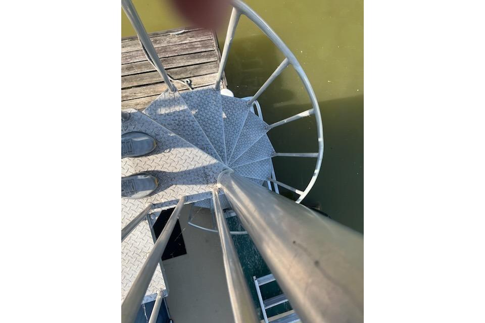 Spiral staircase on 1995 Myacht 40X13 houseboat, overlooking water and dock.