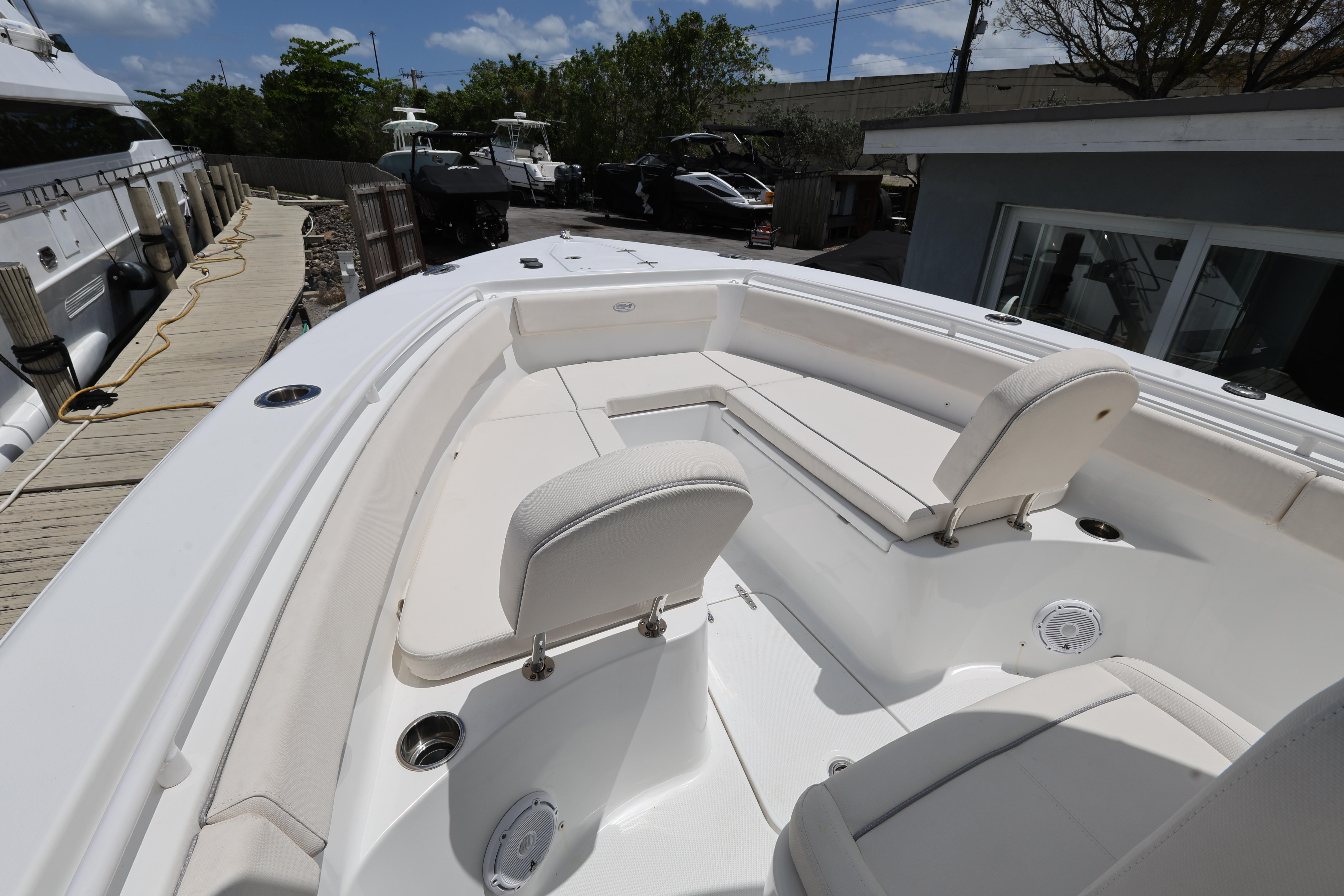 2024 Sea Hunt Gamefish 25 boat interior with white seating and deck, docked outdoors.