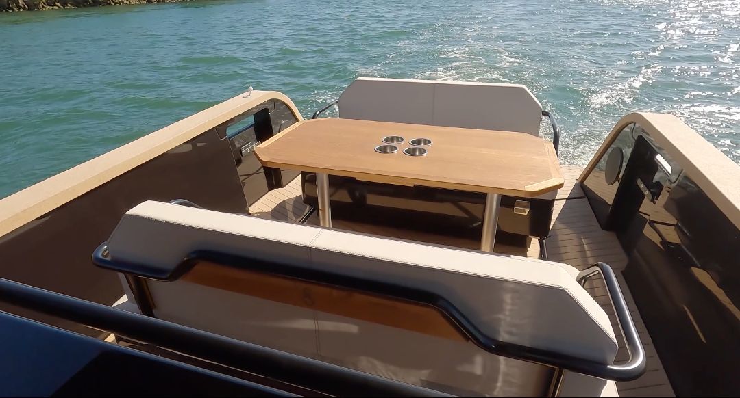The image shows the stern of an X Shore Eelex 8000 boat on the water with a table.
