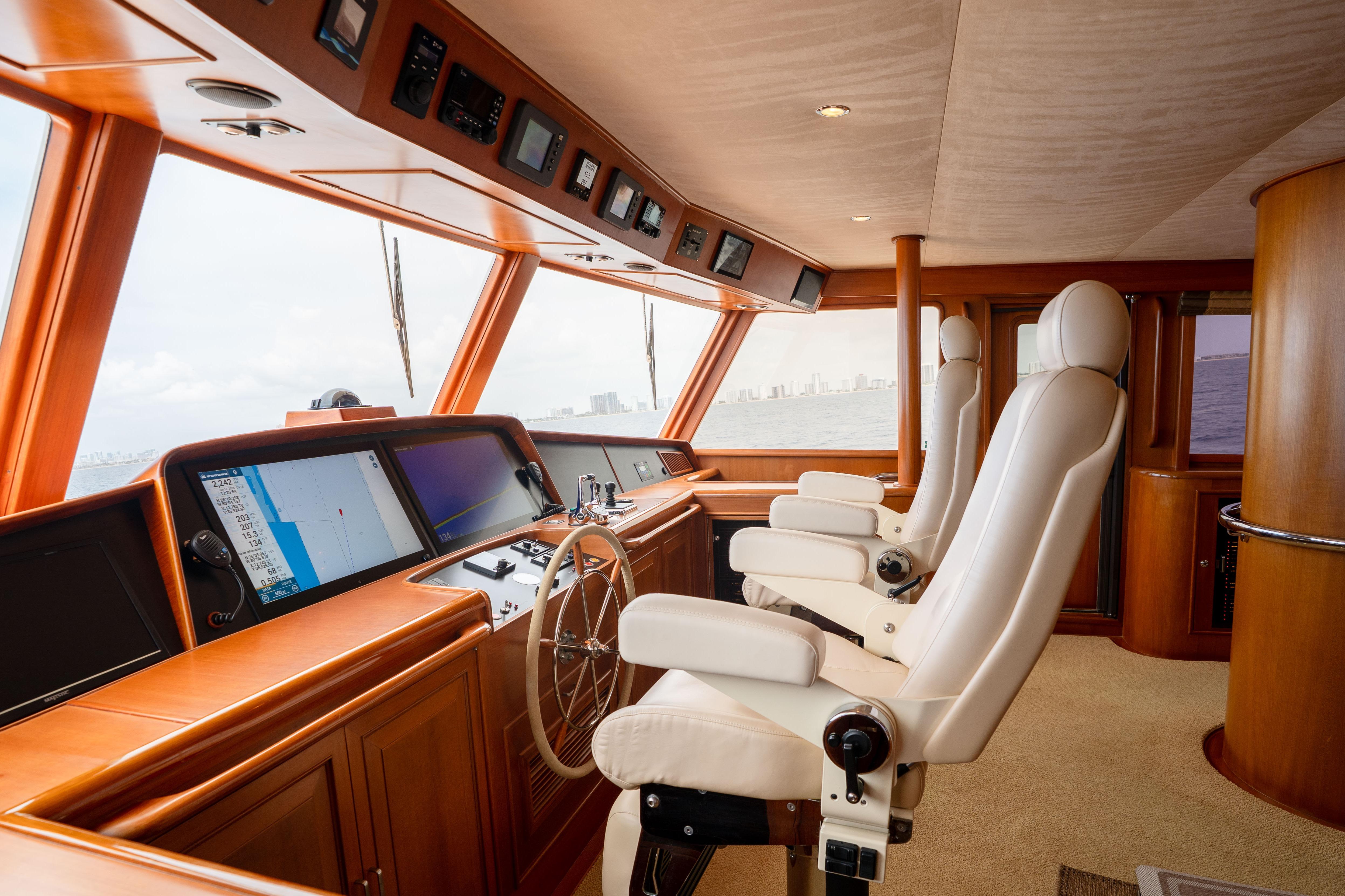 Luxurious helm of a 2006 Fleming 75 yacht with modern navigation equipment and plush seating.