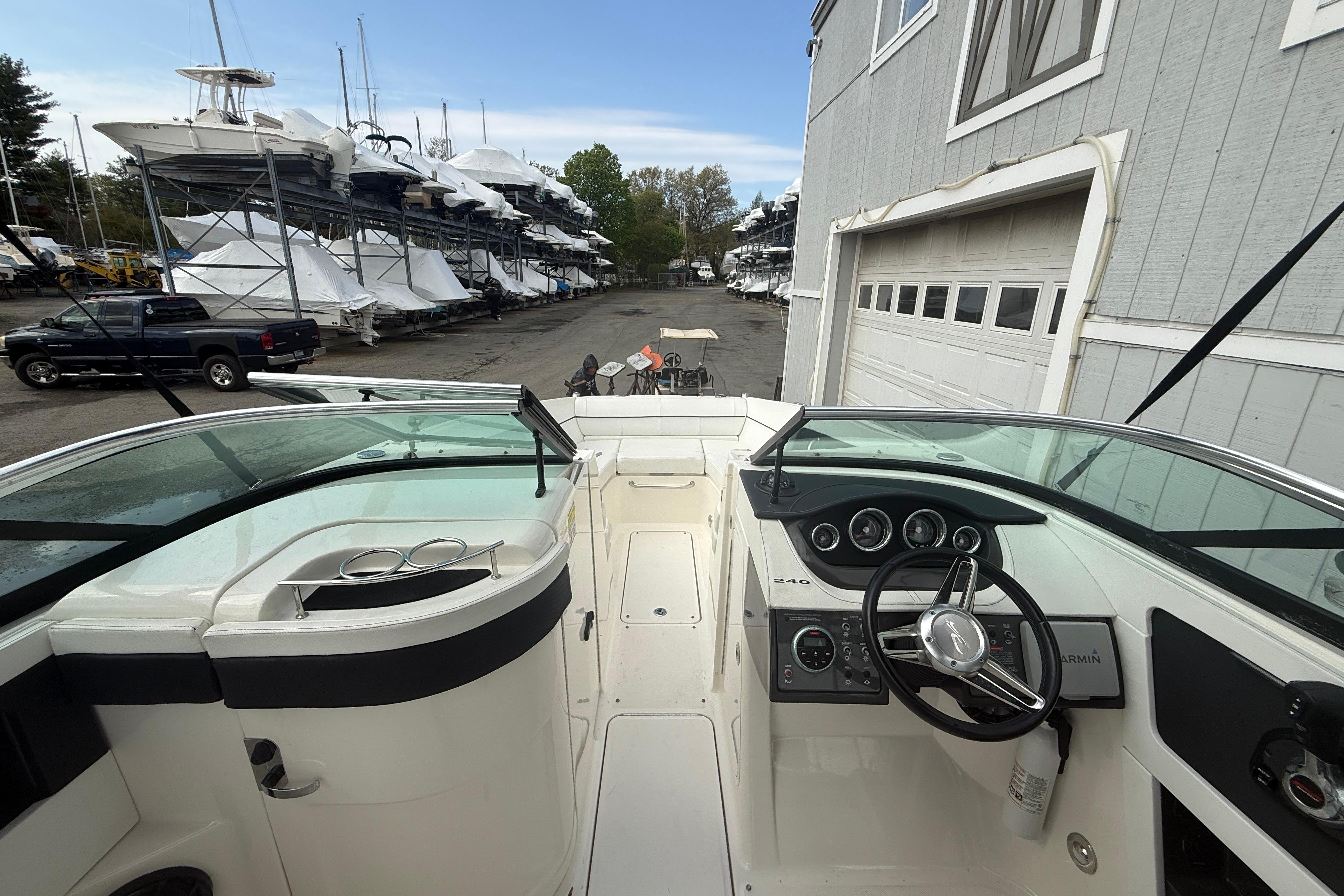 2015 Sea Ray 240 Sundeck boat interior with steering wheel and dashboard, docked near storage facility.