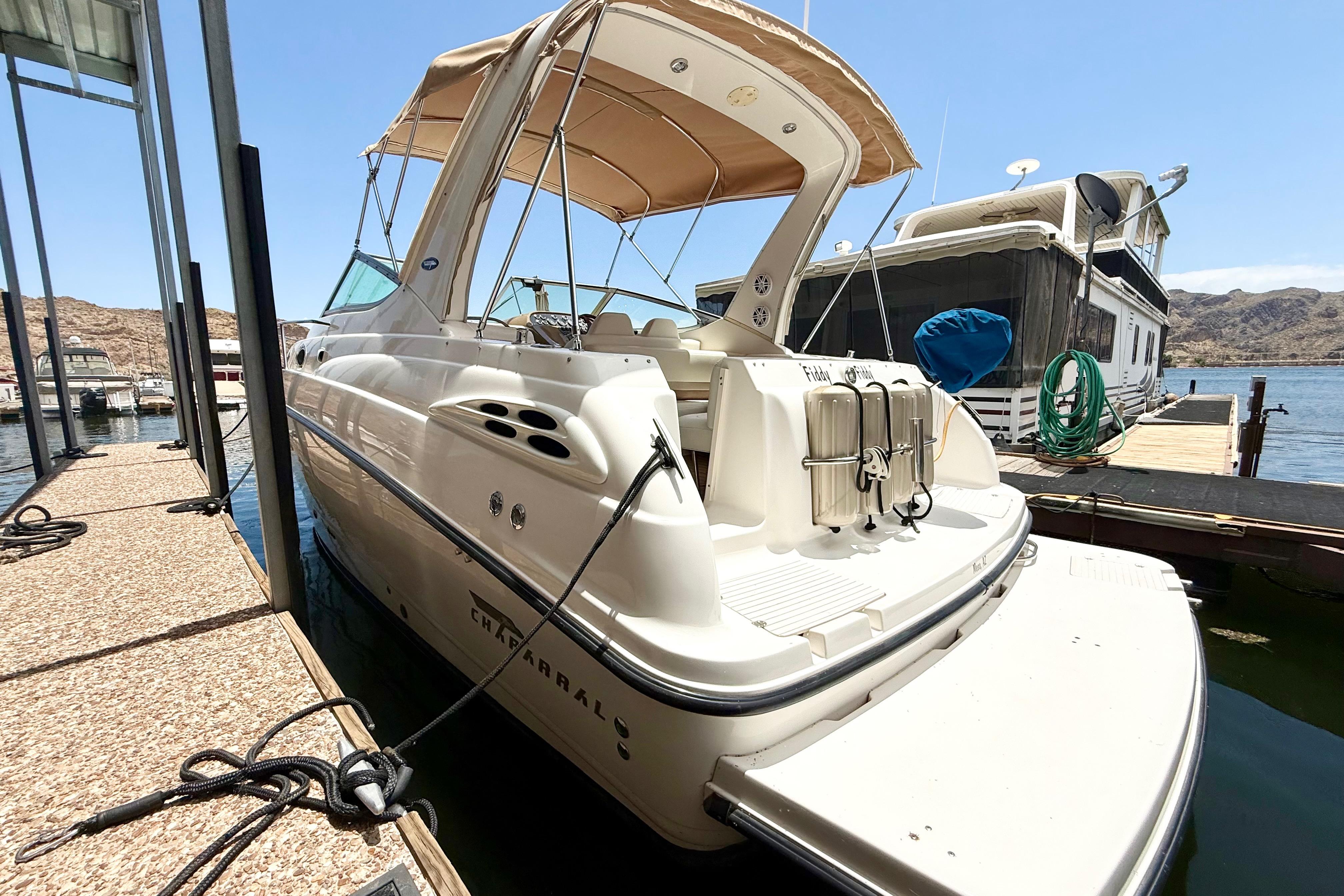 1999 Chaparral Signature 300 boat docked at marina, featuring sleek design and beige canopy.
