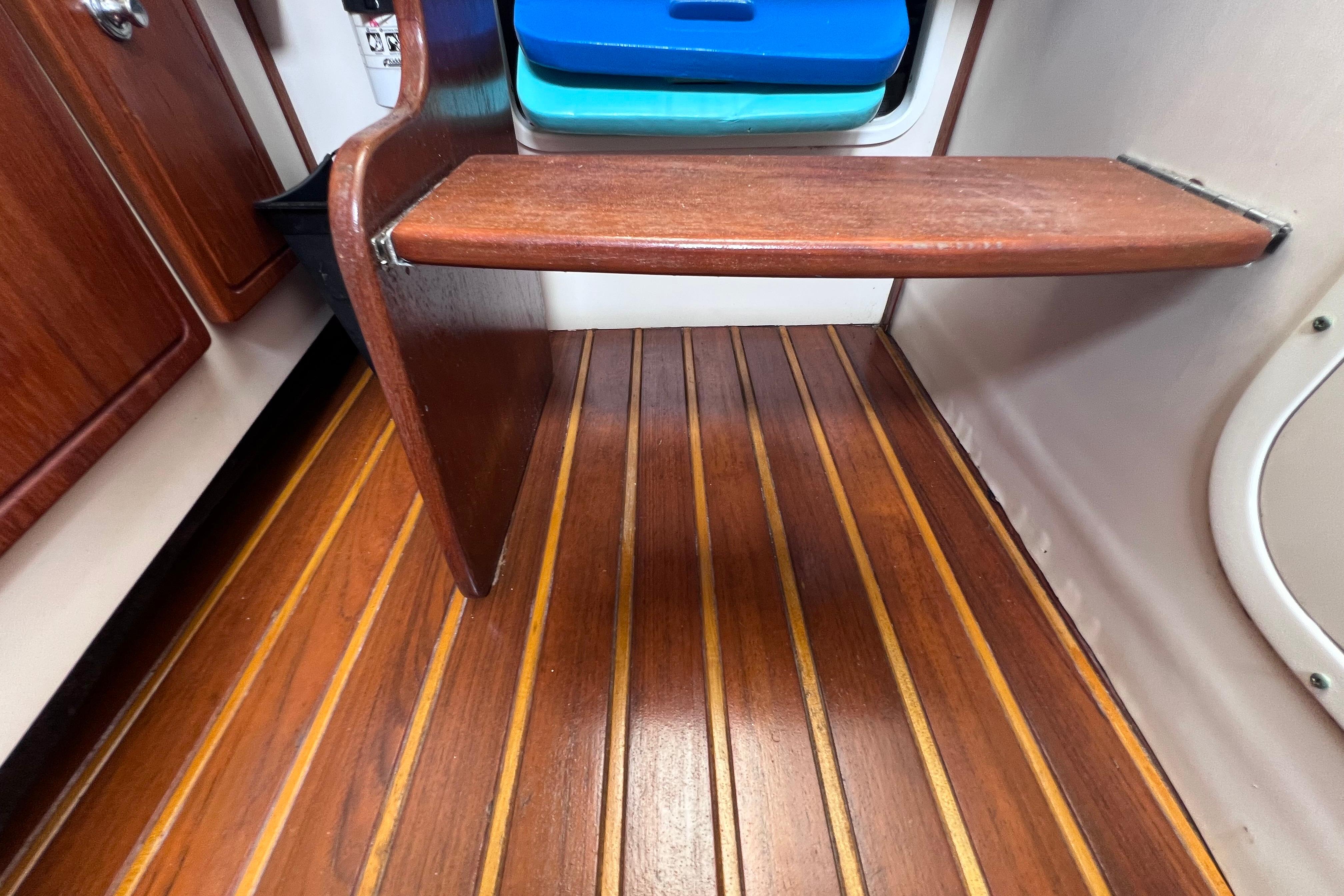 Wooden interior of 2005 Pursuit 3070 Offshore boat, featuring teak flooring and storage shelf.