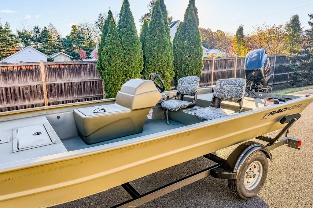 2026 Tracker Grizzly 1754 SC boat on trailer, parked outdoors, with camo seats and motor.