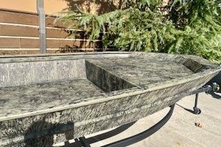 2026 Tracker Grizzly 1754 Utility boat with camouflage design, displayed outdoors.