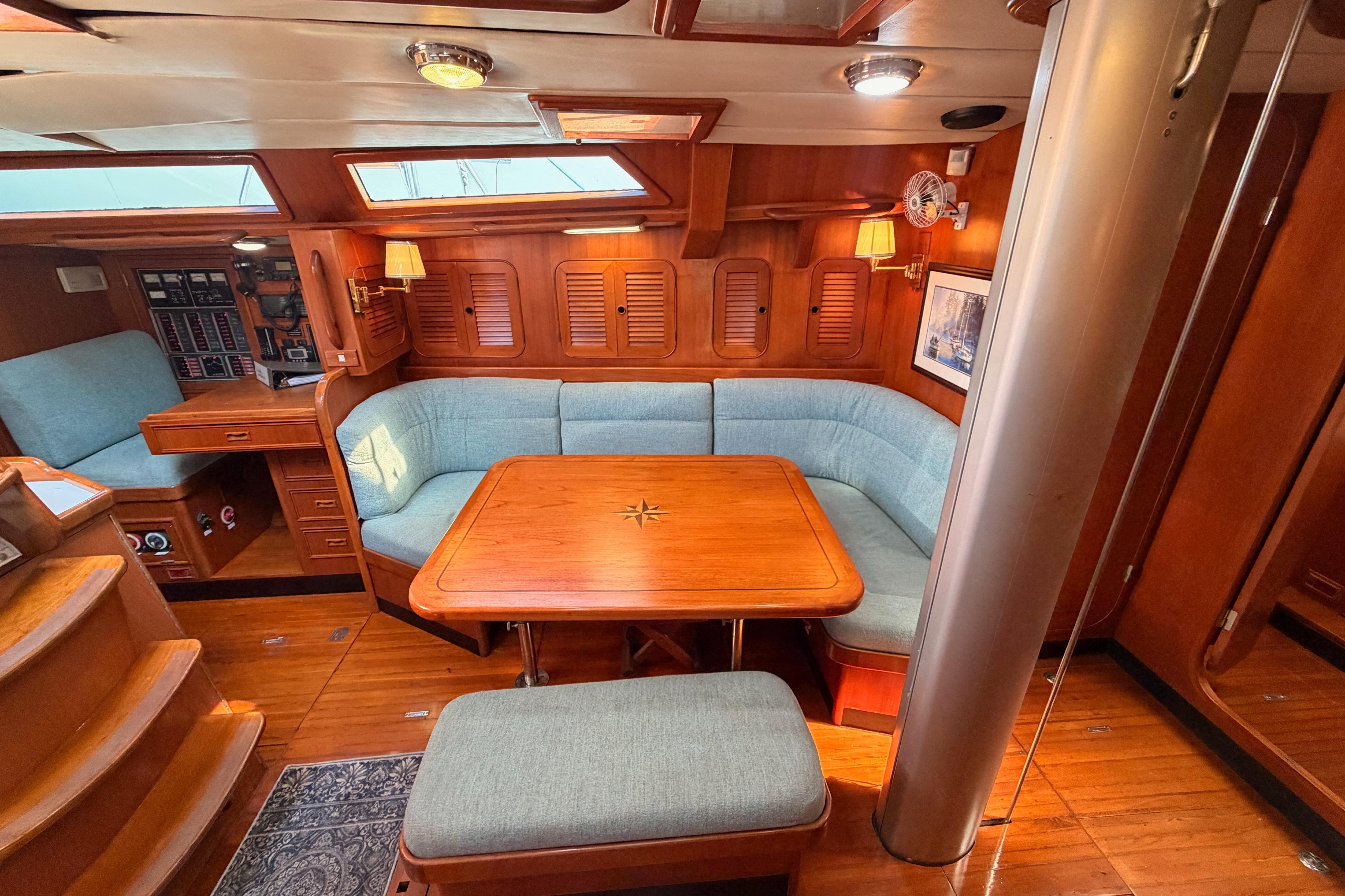 Luxurious 1991 Hylas 51 yacht interior with wooden dining area and blue seating.