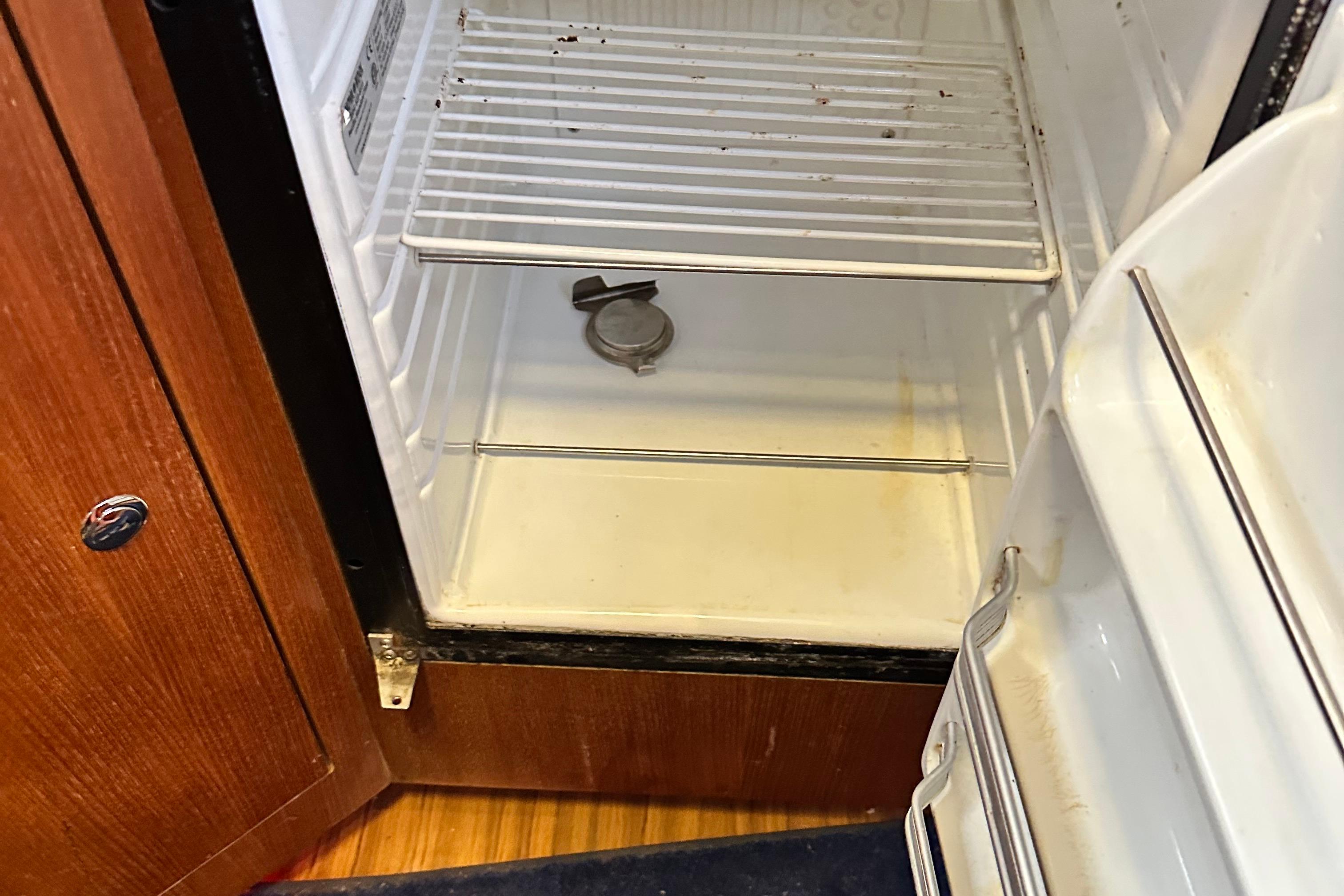 Open refrigerator inside 2006 Hunter 41 Deck Salon yacht, showing empty shelves and wooden cabinetry.
