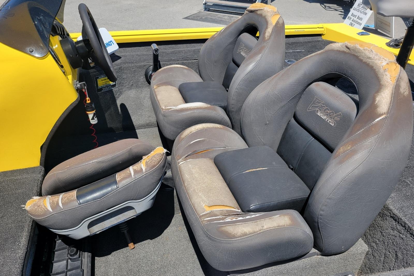 Interior of a 2011 Excel 1751 F4 boat with worn seats and steering wheel.