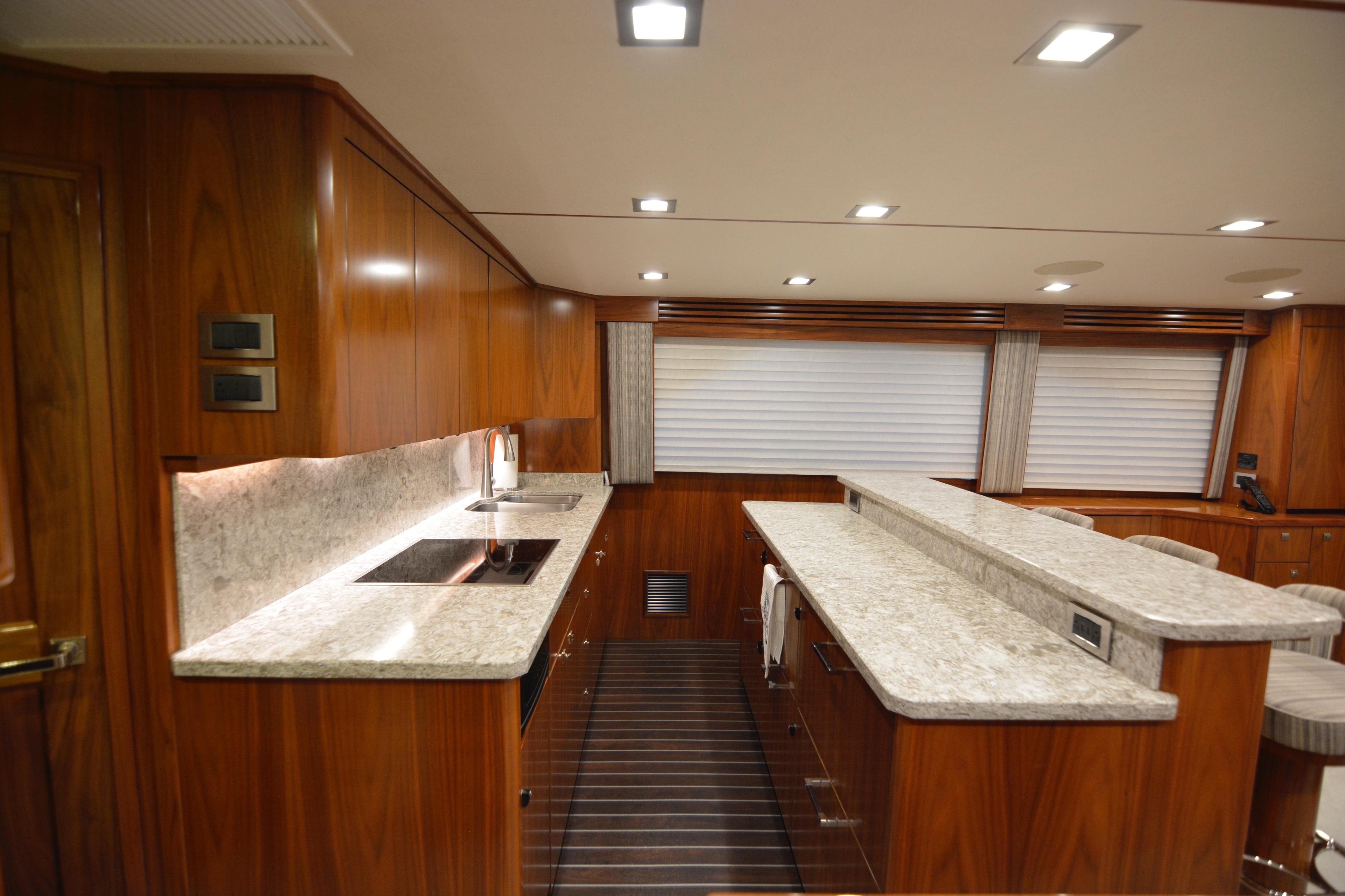 Luxurious kitchen interior of 2019 Viking 68 Convertible yacht with wood cabinetry and marble countertops.