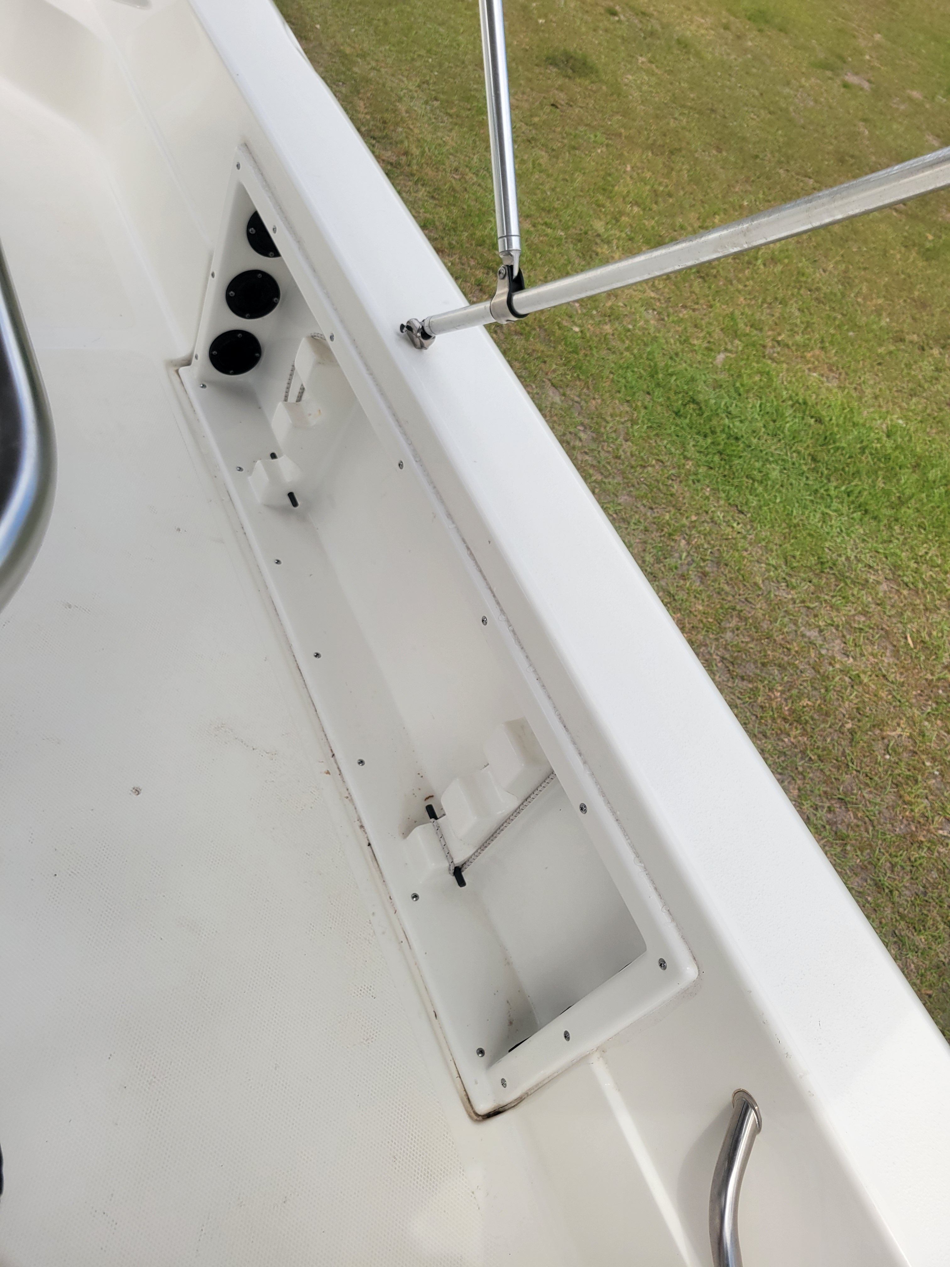 Interior view of a boat with white deck and stainless steel railing.