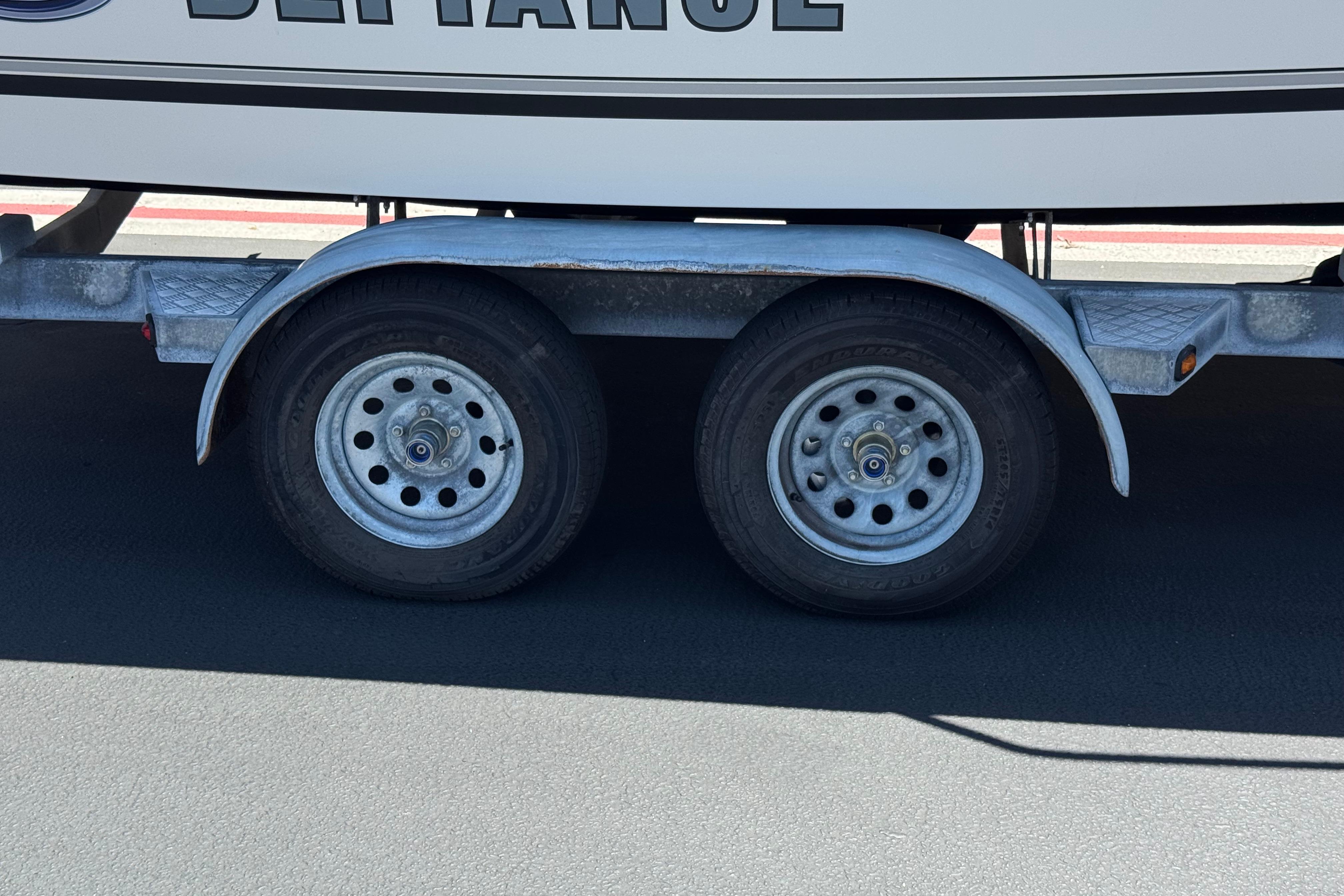 Trailer wheels of a 2017 Defiance Admiral 220 EX boat on pavement.