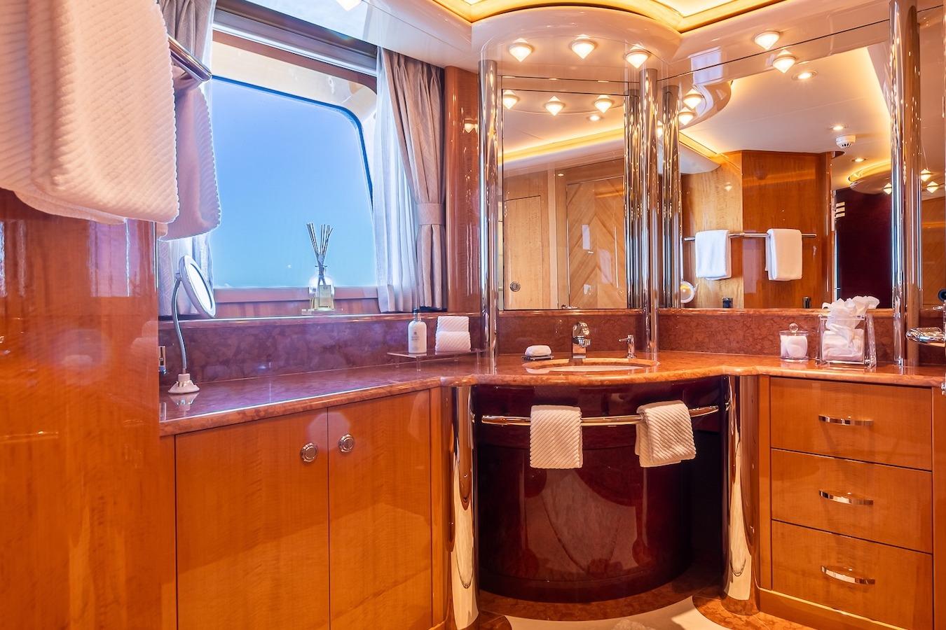 Luxurious yacht bathroom with wood finishes, elegant lighting, and modern fixtures on a 2001 Feadship Custom.