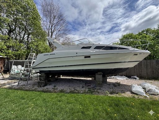 1998 Bayliner 2855 Ciera Sunbridge on a dry dock in a backyard.