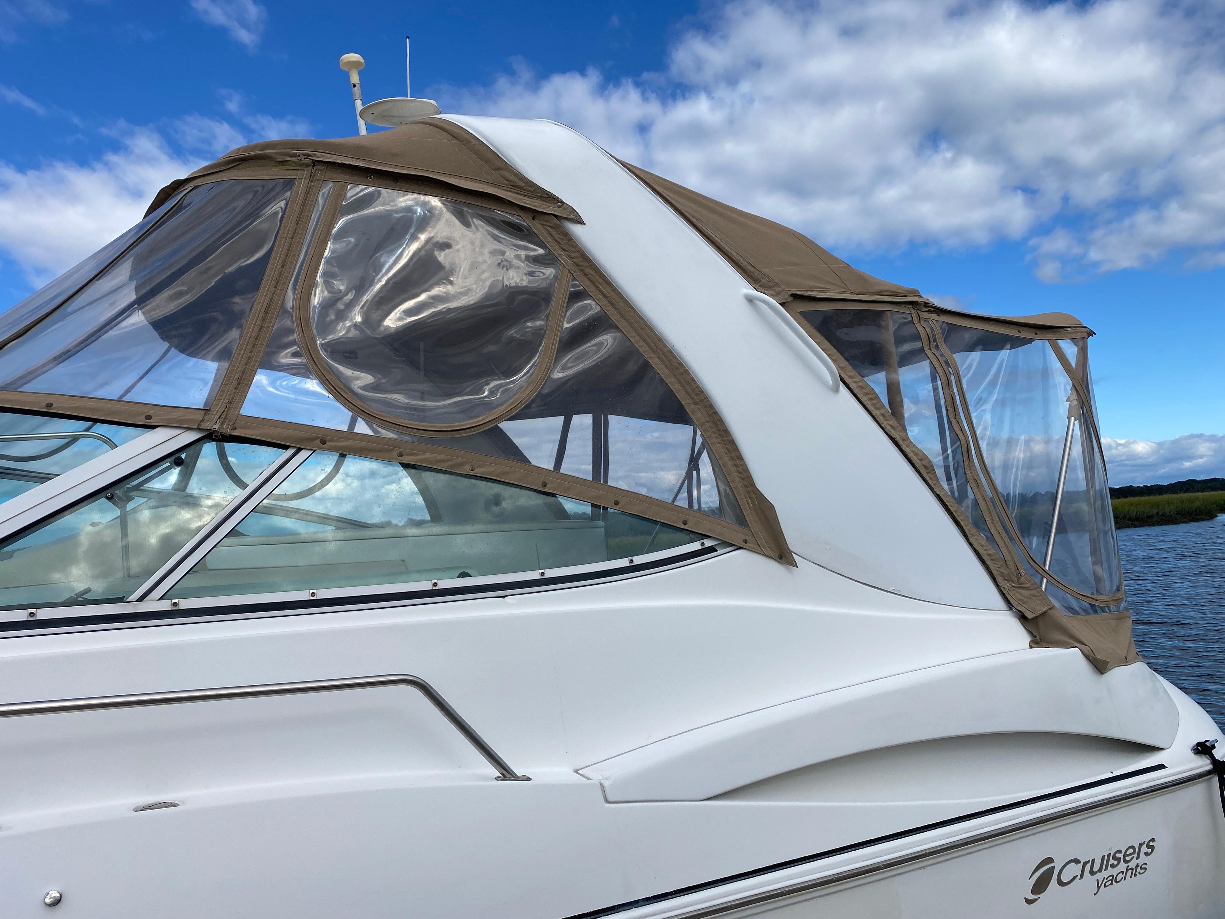 2000 Cruisers 3672 yacht with tan canopy, docked under a blue sky.