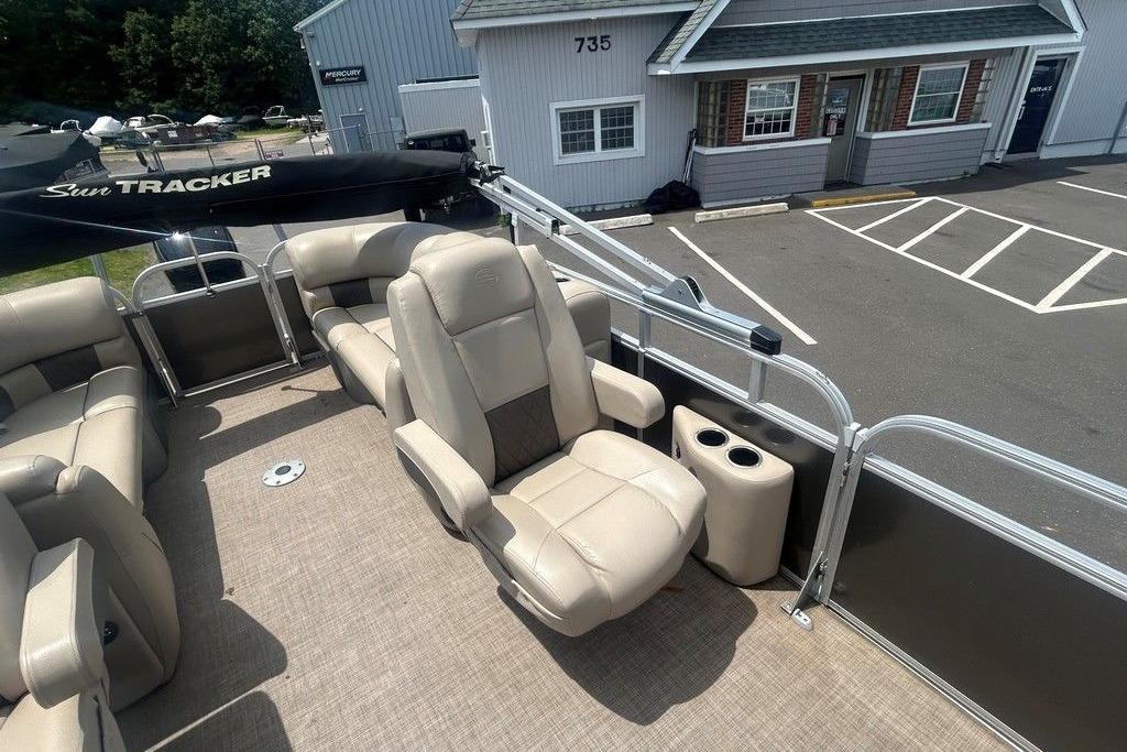 2023 Sun Tracker Party Barge 22 DLX with beige seating, parked near a building.