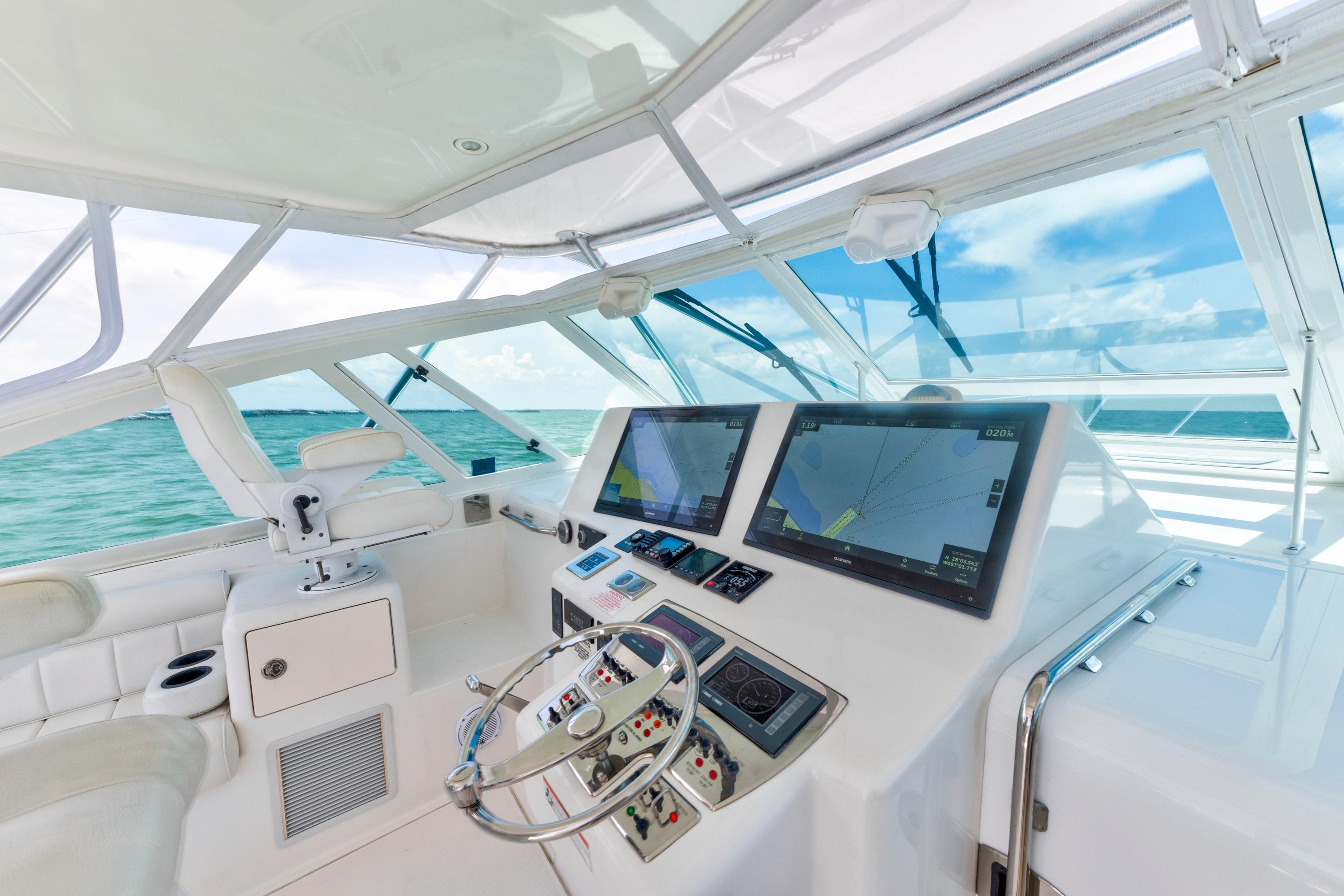 Helm of 2010 Cabo 45 Express yacht with dual navigation screens, steering wheel, and ocean view.