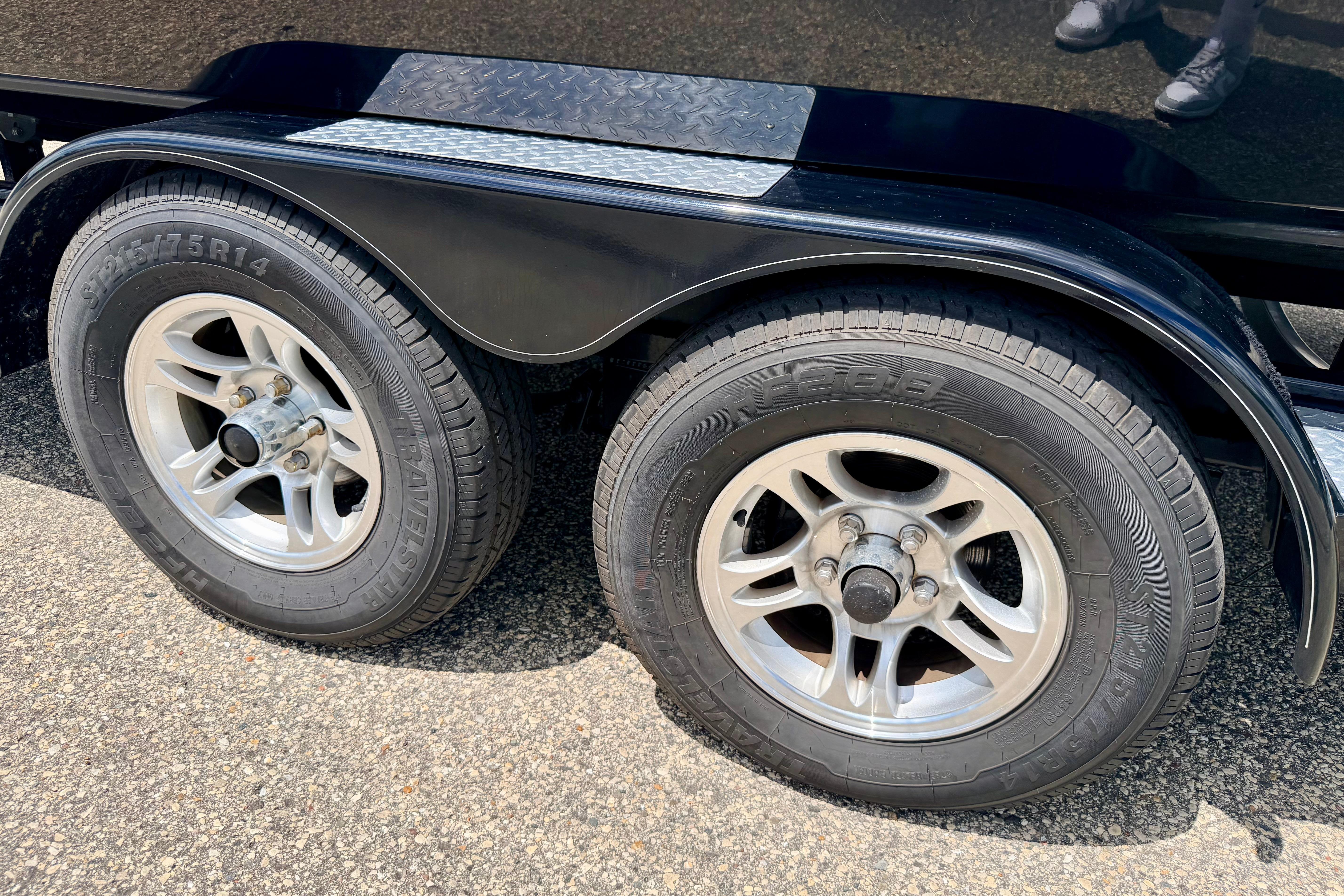 Trailer wheels of a 2015 Chaparral Sunesta 264 on asphalt surface.