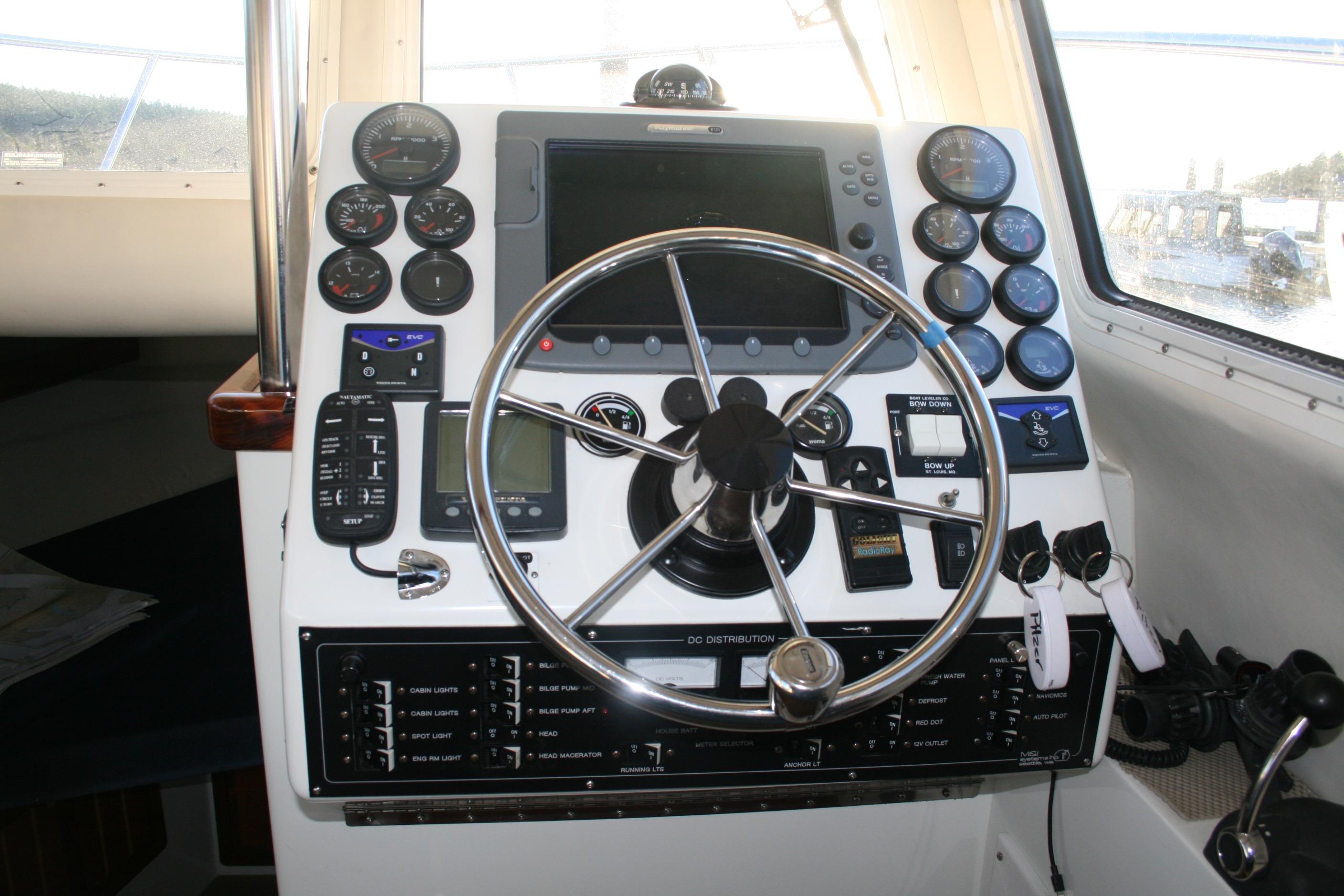 Control panel of a 2005 Ocean Sport 30' boat with steering wheel and gauges.