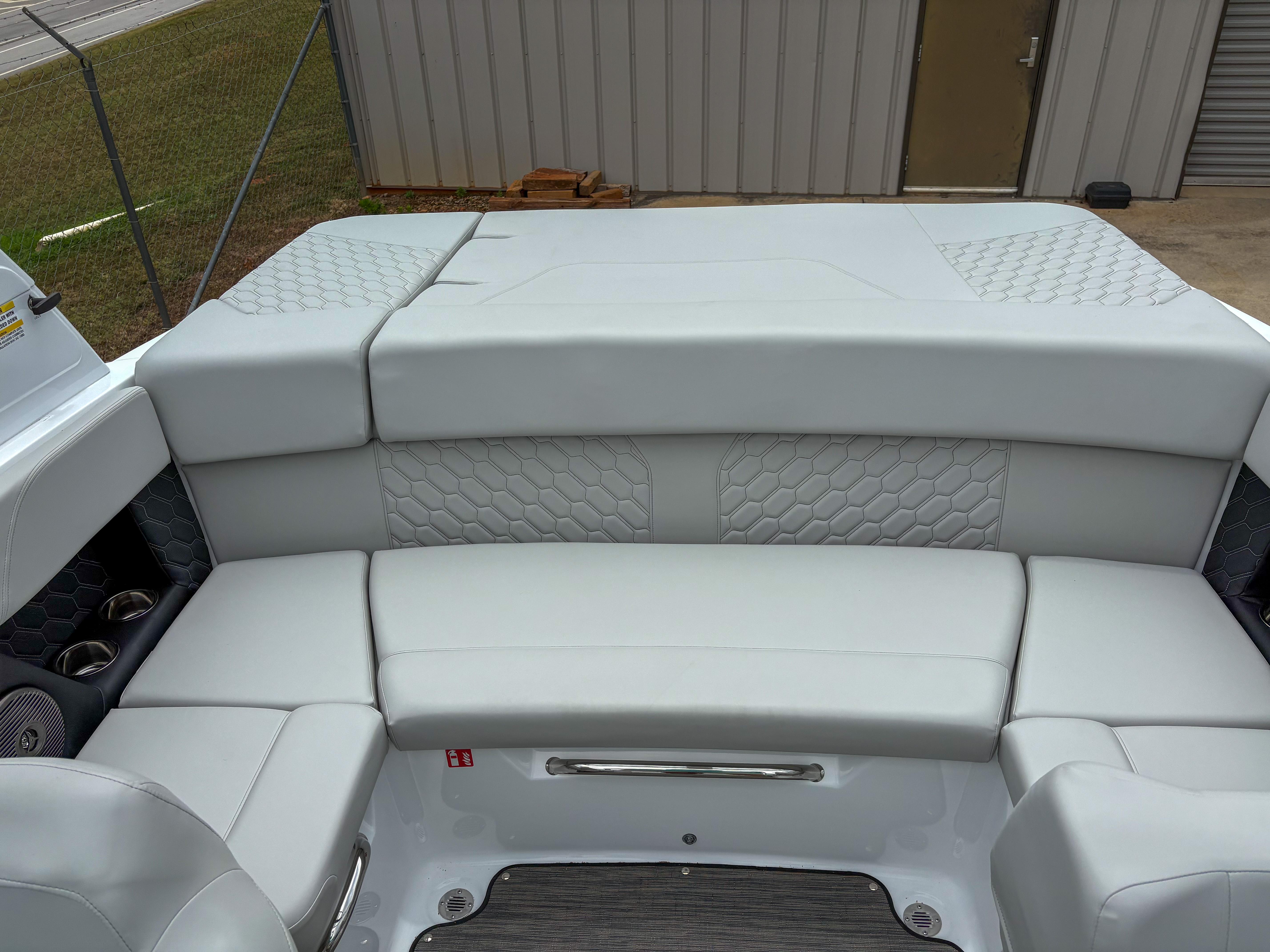 2026 Four Winns H2 Freedom boat interior with gray cushioned seating and hexagonal pattern.