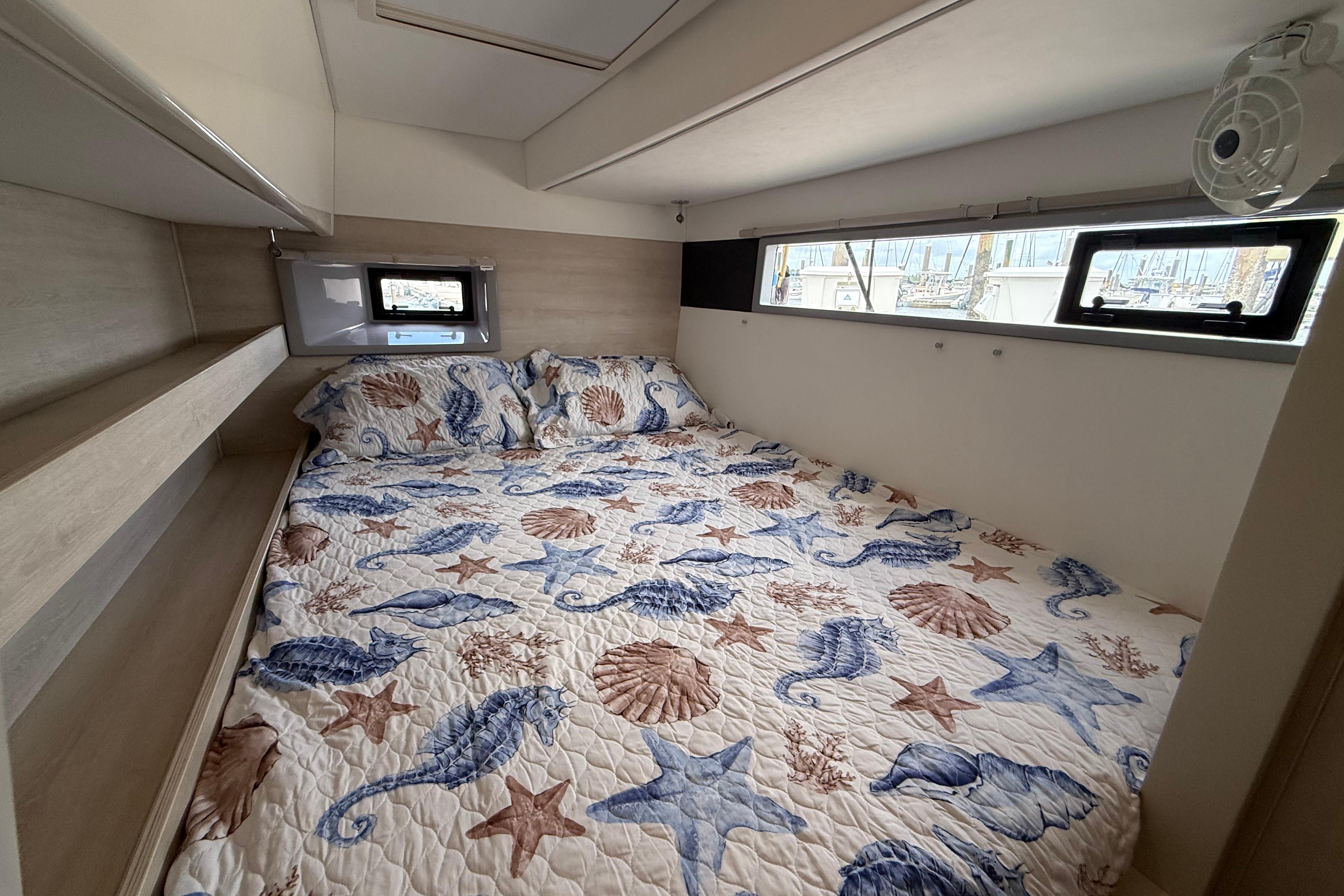 Cozy bedroom in 2021 Leopard 43 Powercat with nautical-themed bedding and ample natural light.