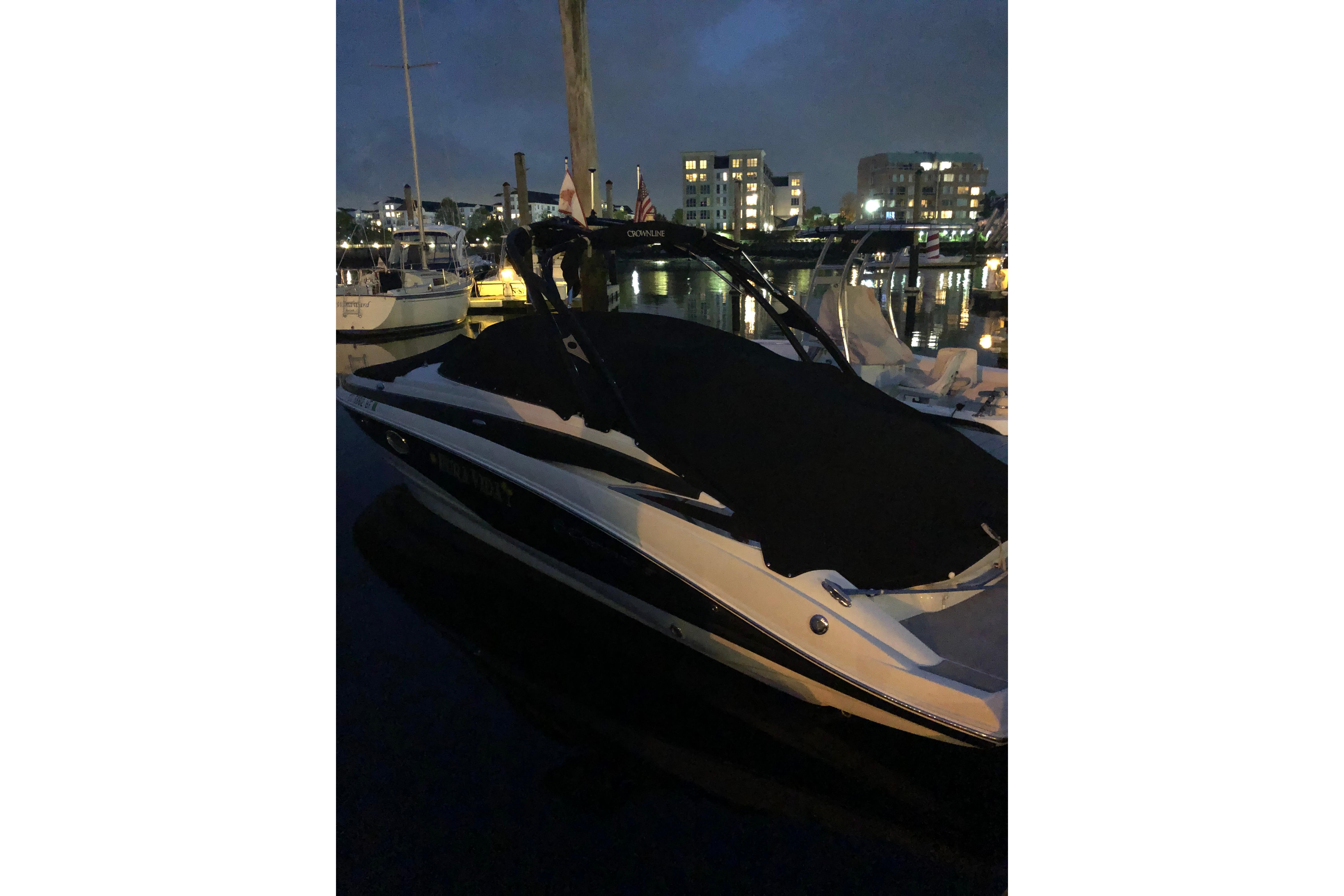 2013 Crownline Eclipse E4 boat docked at night, covered, with city lights in background.