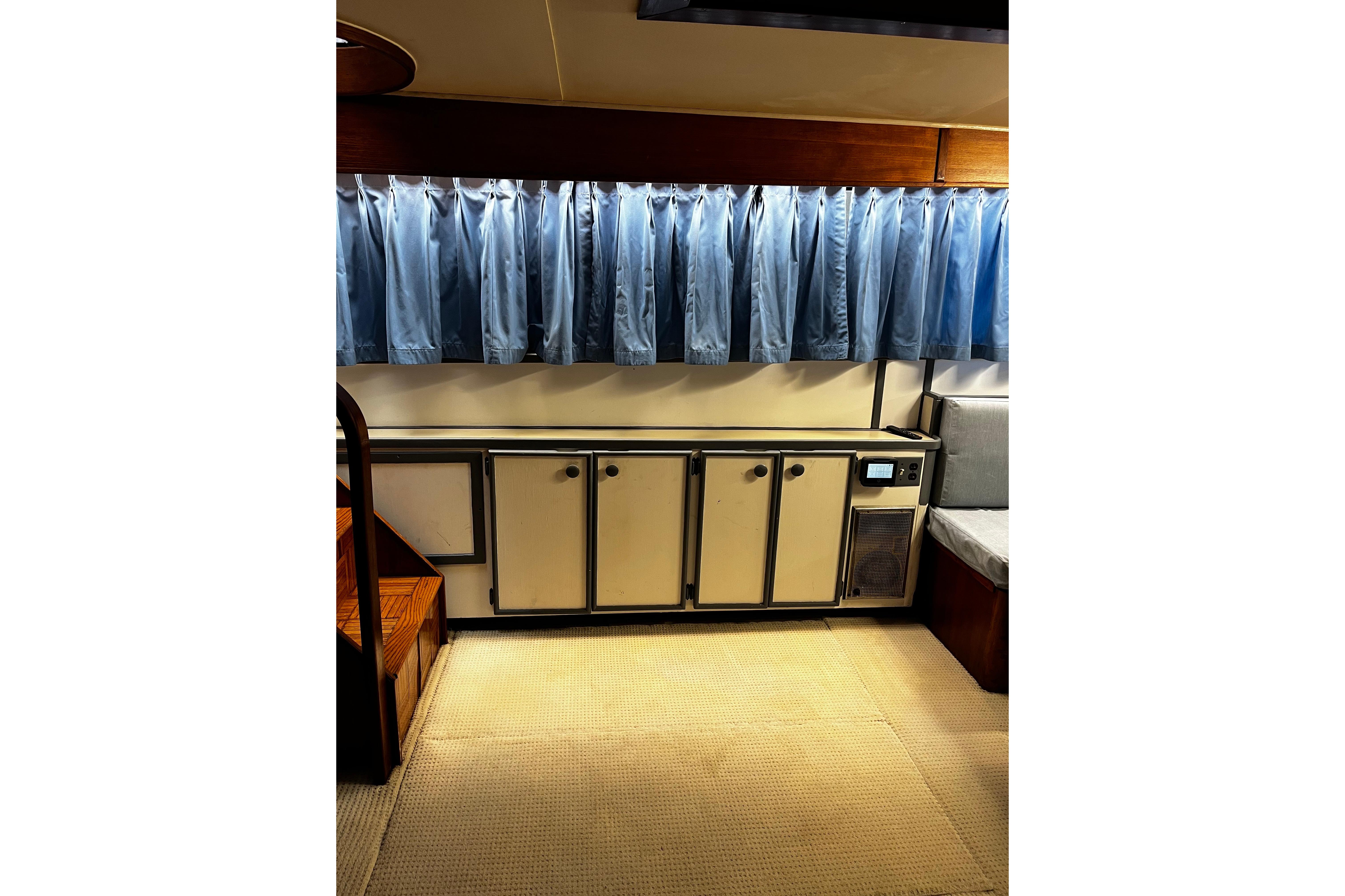 Interior of 1988 Chris Craft Constellation with blue curtains and vintage cabinetry.