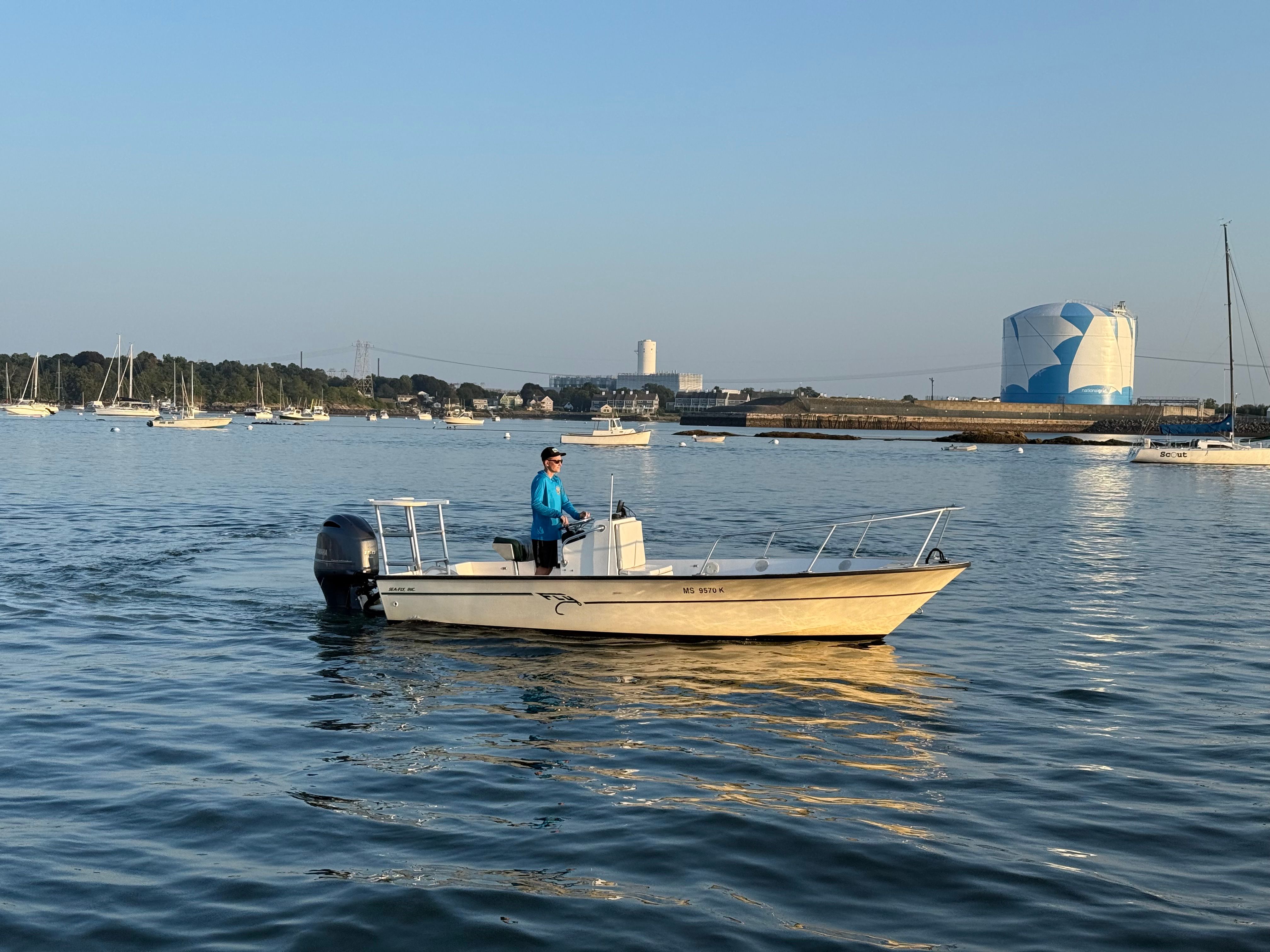 A person navigates a 2004 Custom Sea Fly boat on a calm harbor.