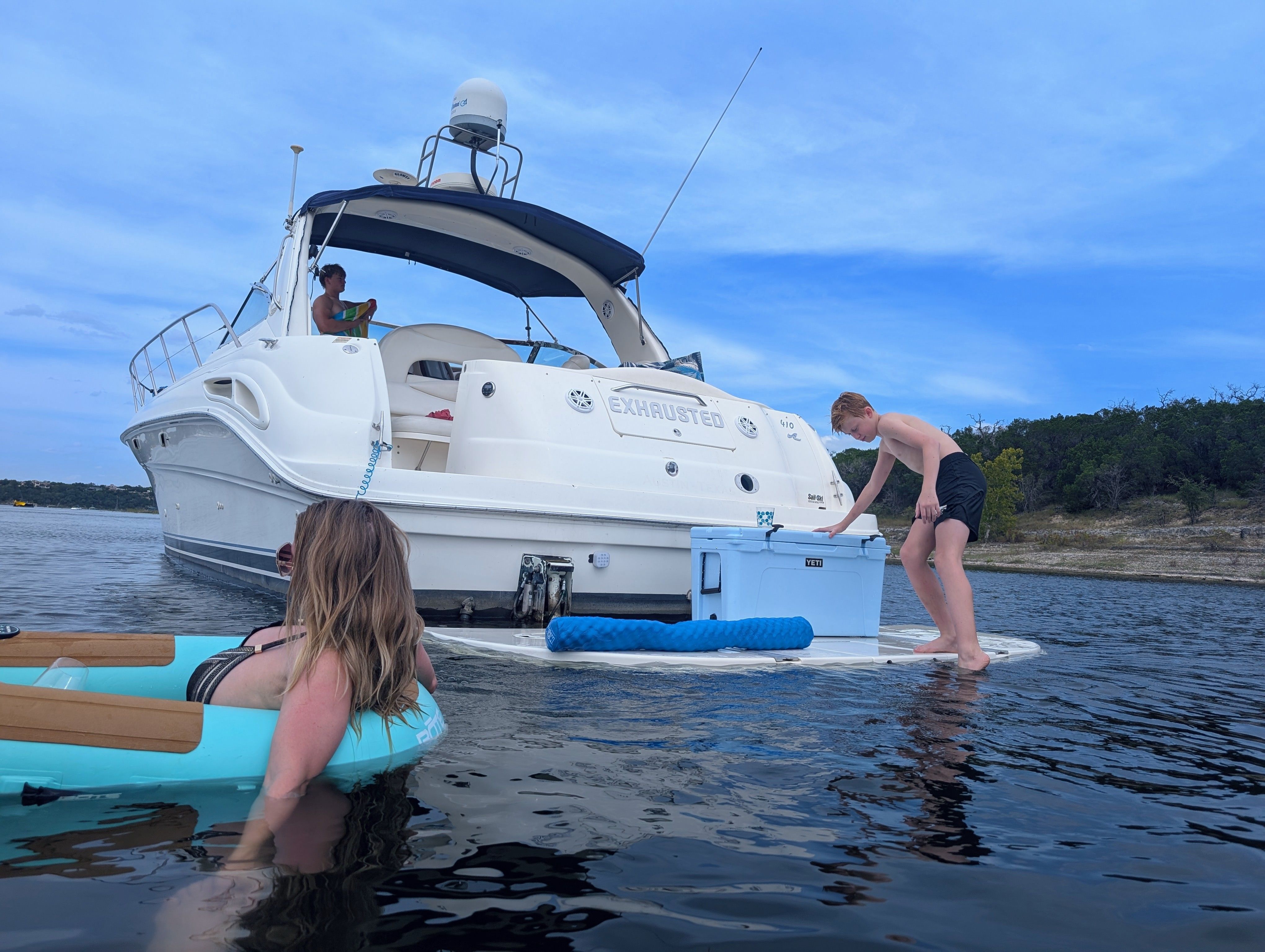 People relaxing on a 2000 Sea Ray Sundancer boat in the water.