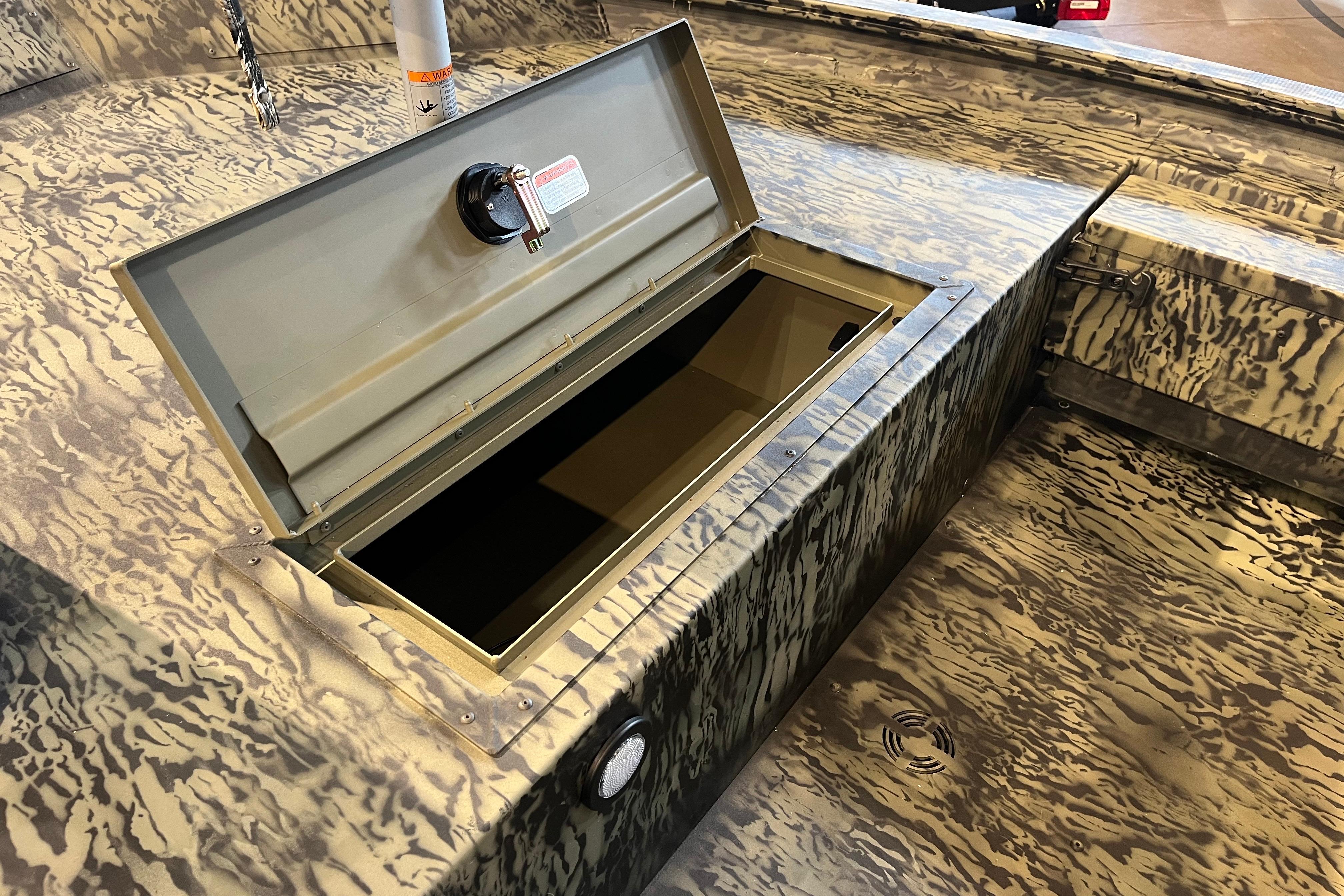 Open storage compartment on 2026 Tracker Grizzly 1654 T Sportsman boat with camouflage pattern.
