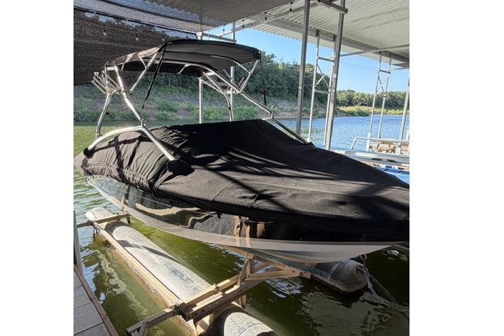 2007 Four Winns 200 Horizon boat with black cover on a lift by the water.