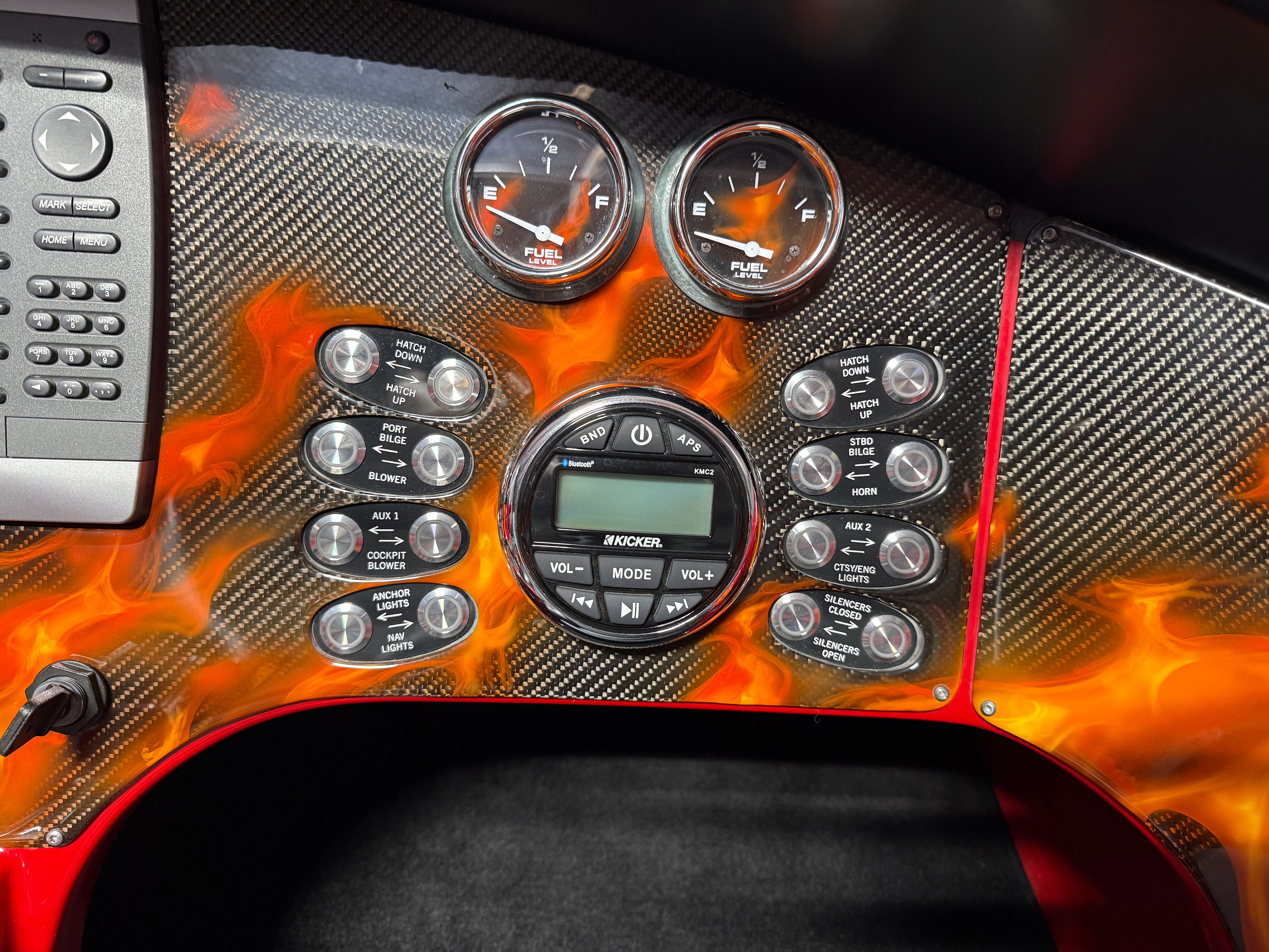 The dashboard of a 2010 MTI CAT with carbon fiber look and flame design, featuring various gauges and controls.