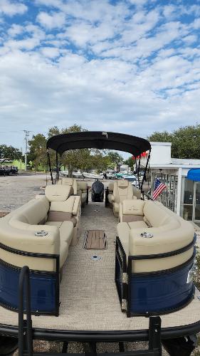 2024 Regency 230 LE3 pontoon boat with beige seating and black canopy.