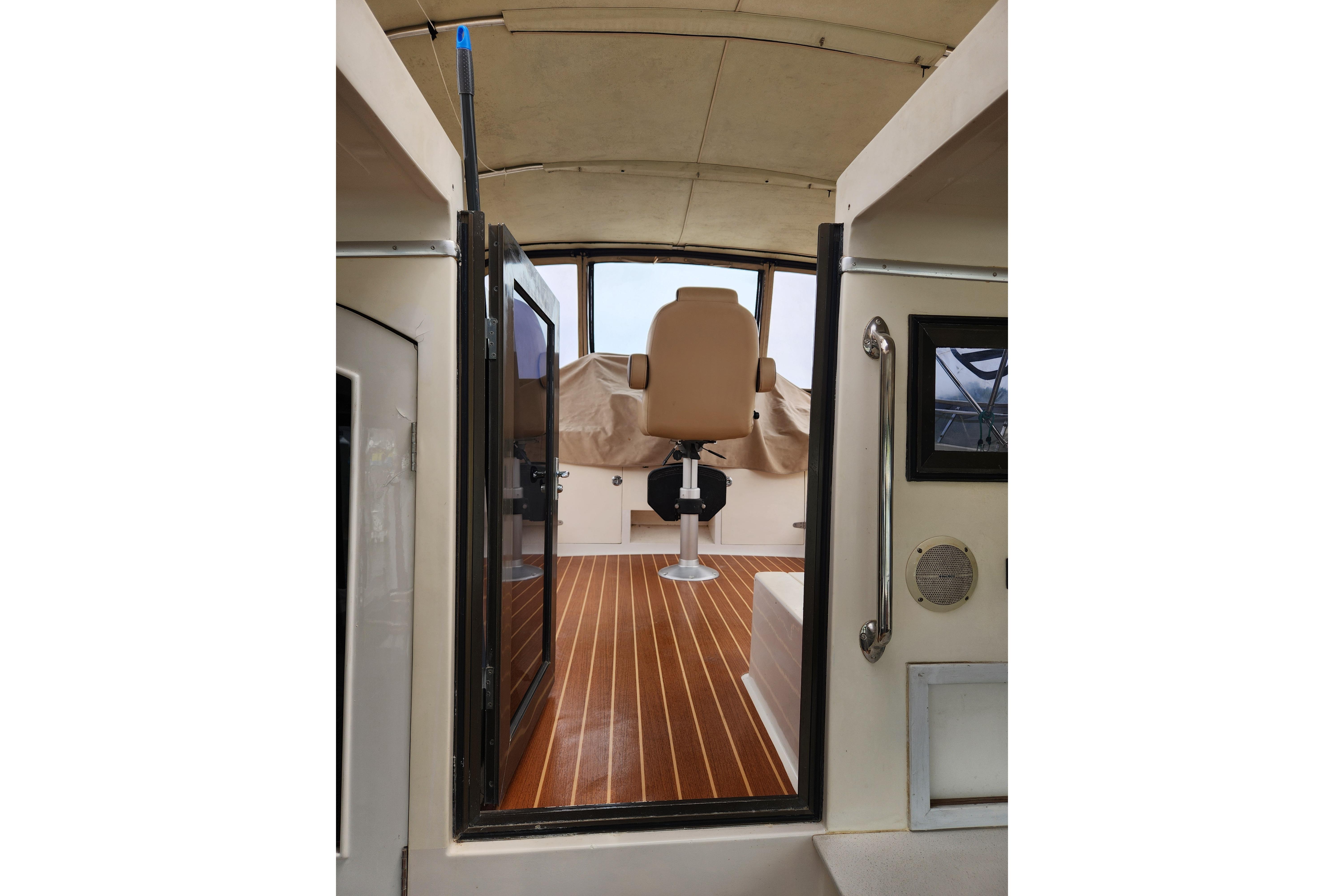 Interior view of 1989 Hyatt Double Cabin Motoryacht with wooden flooring and captain's chair.