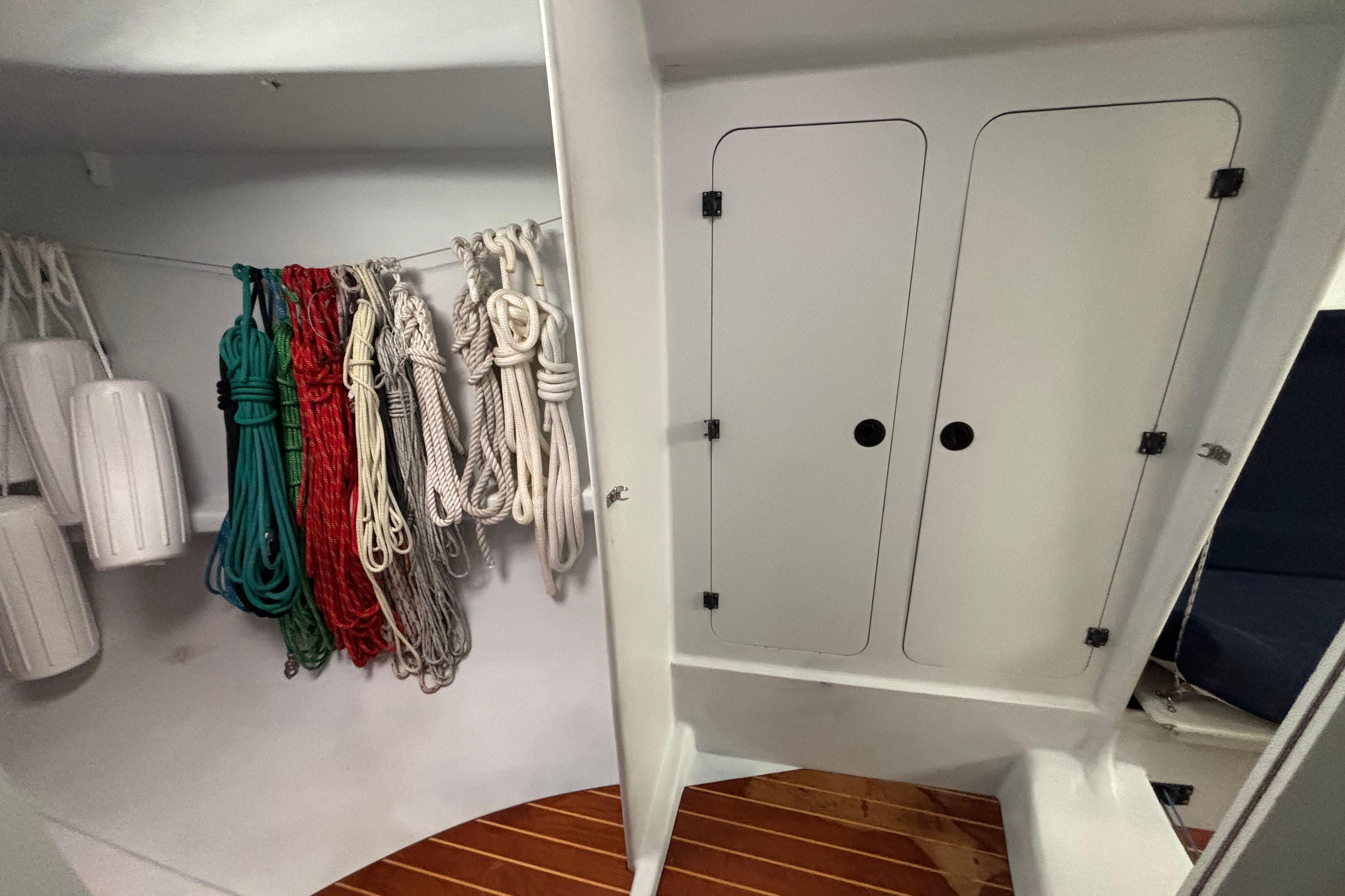 Storage area on a 1995 Tripp 47 sailboat with ropes and fenders neatly organized.