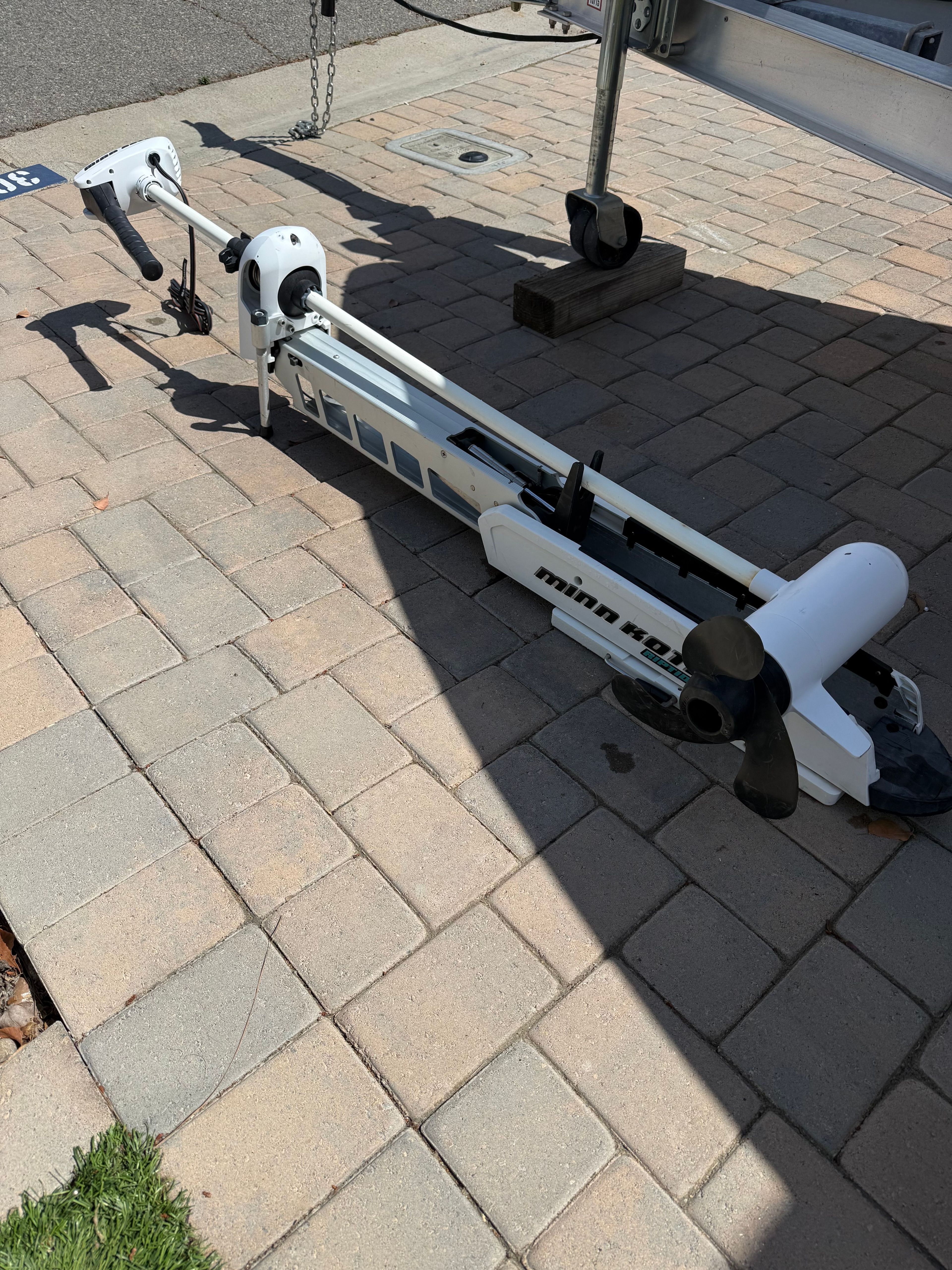 Minn Kota trolling motor on pavement next to Robalo 2100 Bay Hunter.