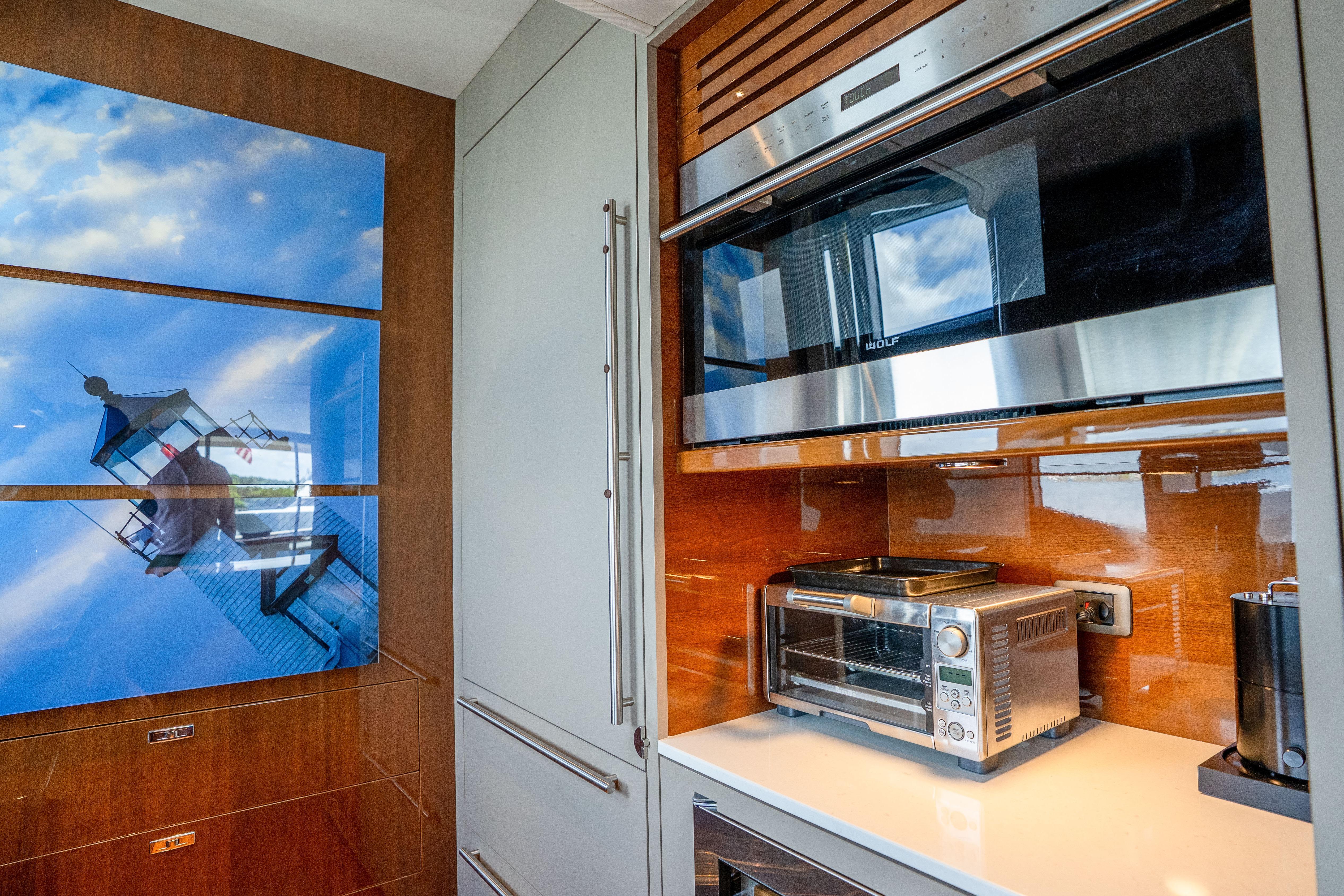 Modern kitchen interior on 2020 Princess Y85 yacht with appliances and lighthouse artwork.