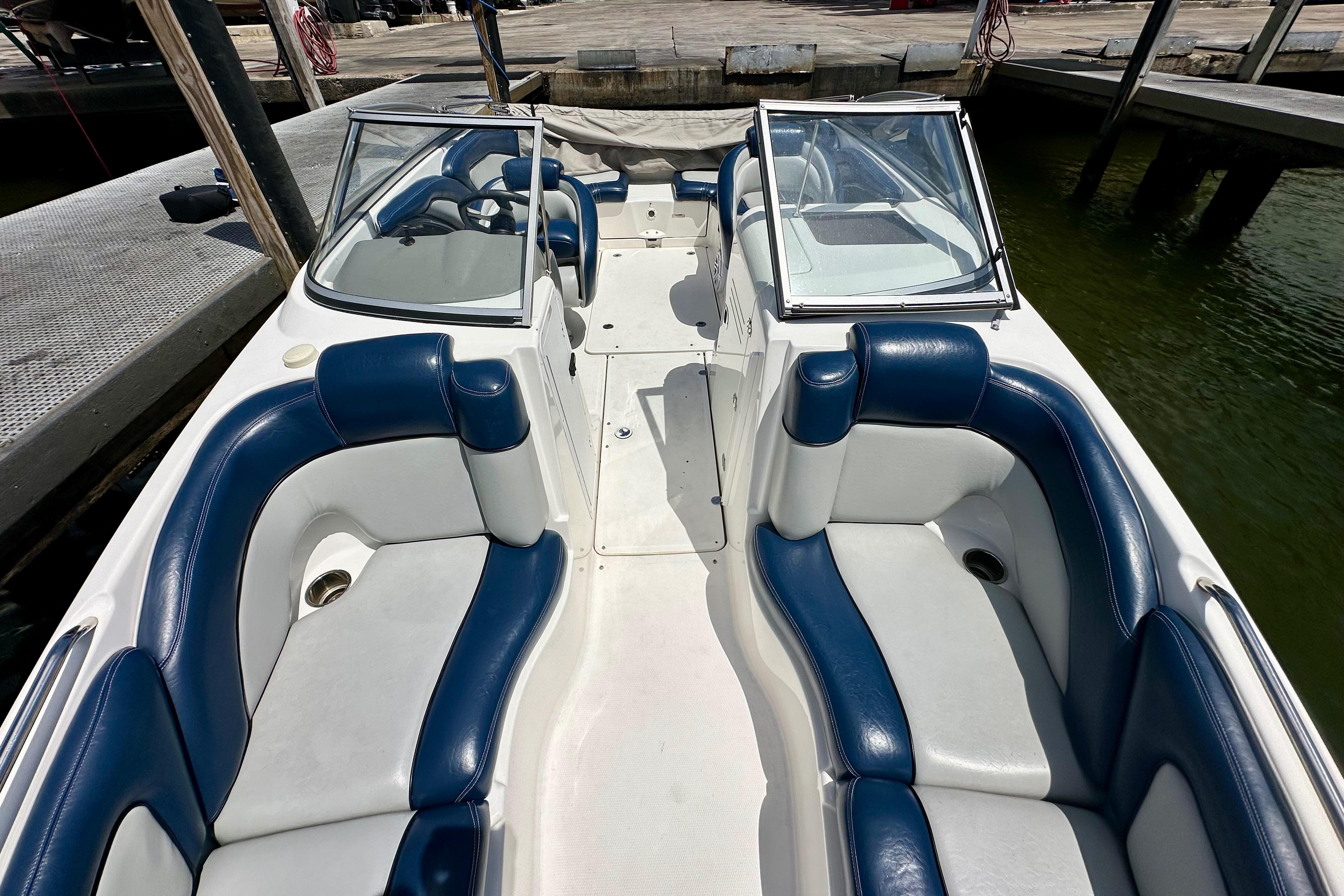 2011 Yamaha Boats 242 Limited interior with blue and white seating, docked by the water.