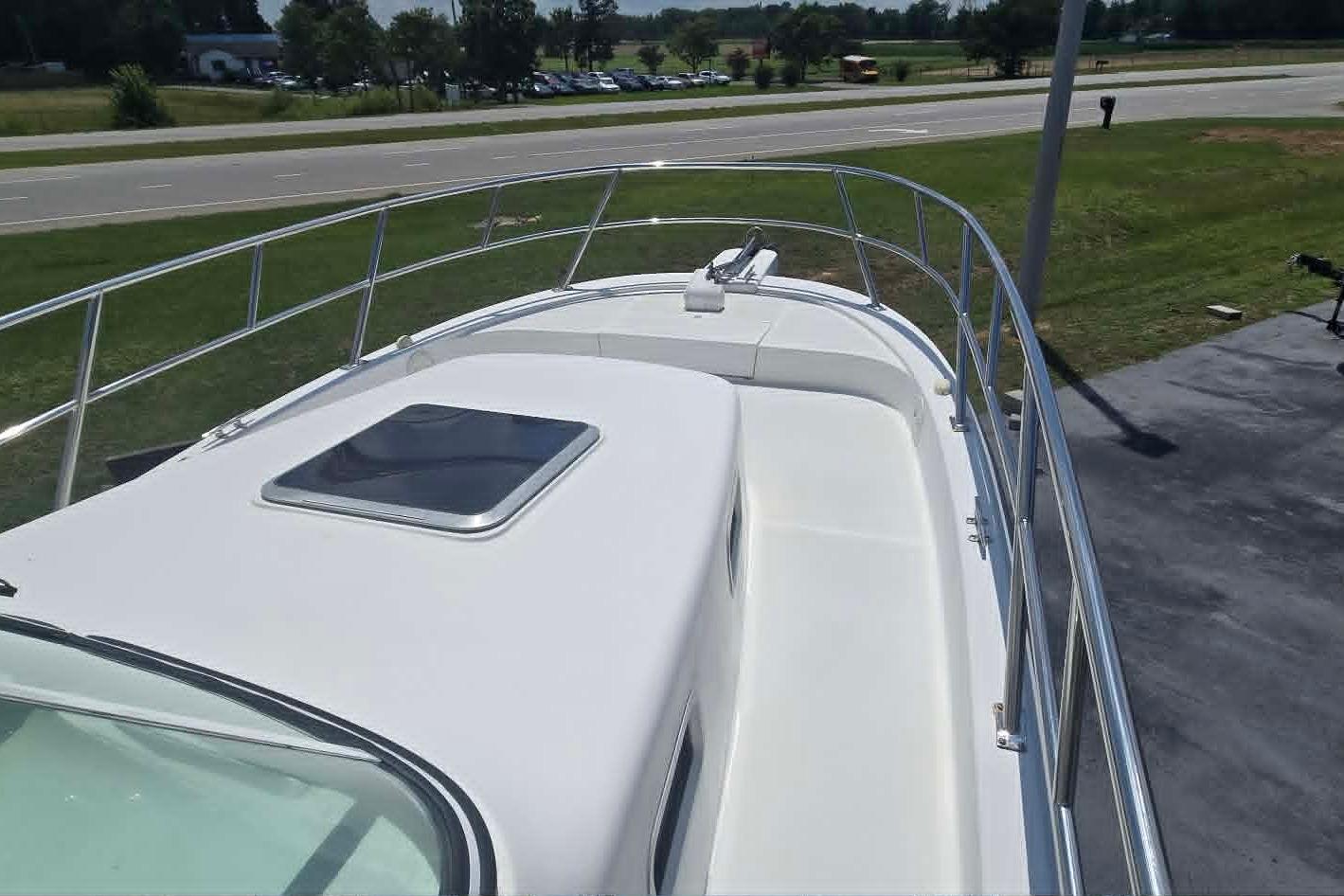 2003 True World Marine 286 boat deck with railing and hatch, parked near a road.