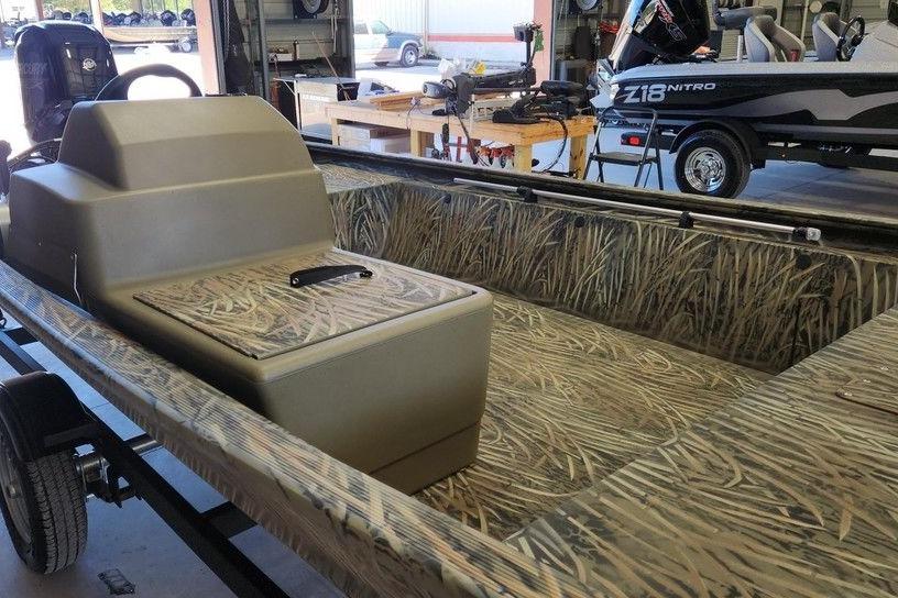 2026 Tracker Grizzly 1648 SC boat with camouflage interior in a workshop setting.