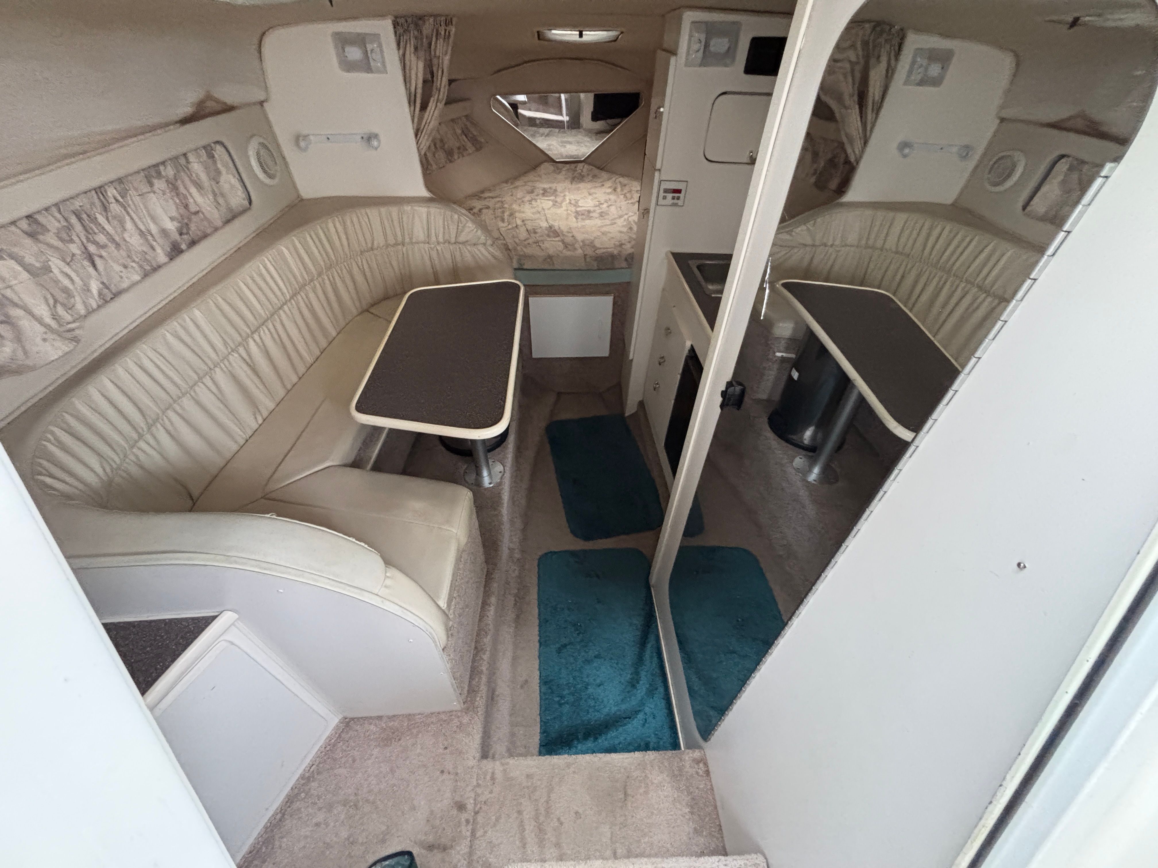 Interior of a yacht with seating area, table, and kitchenette.