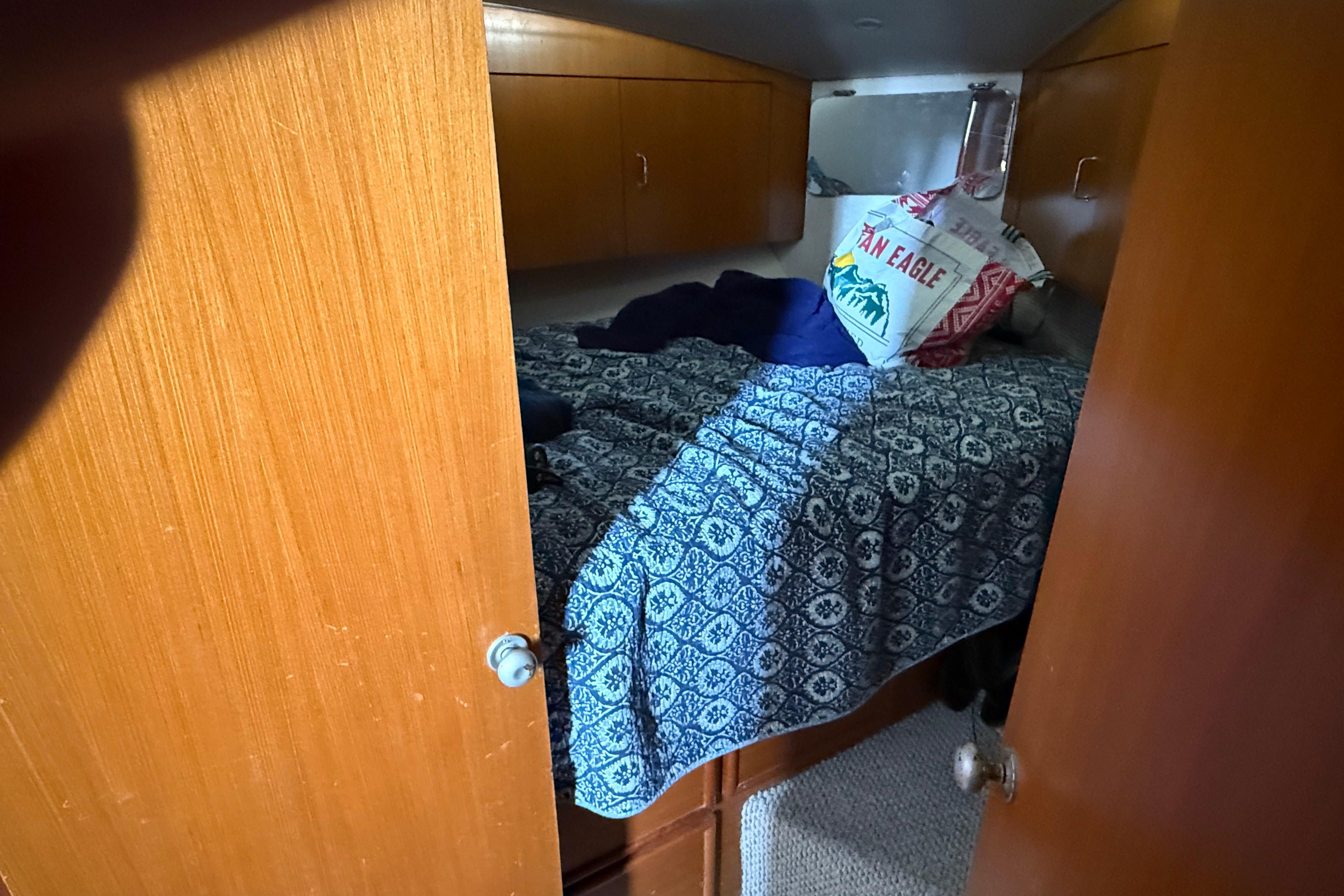 1999 Ocean Yachts 40 Express cabin with blue patterned bedding and wooden cabinetry.