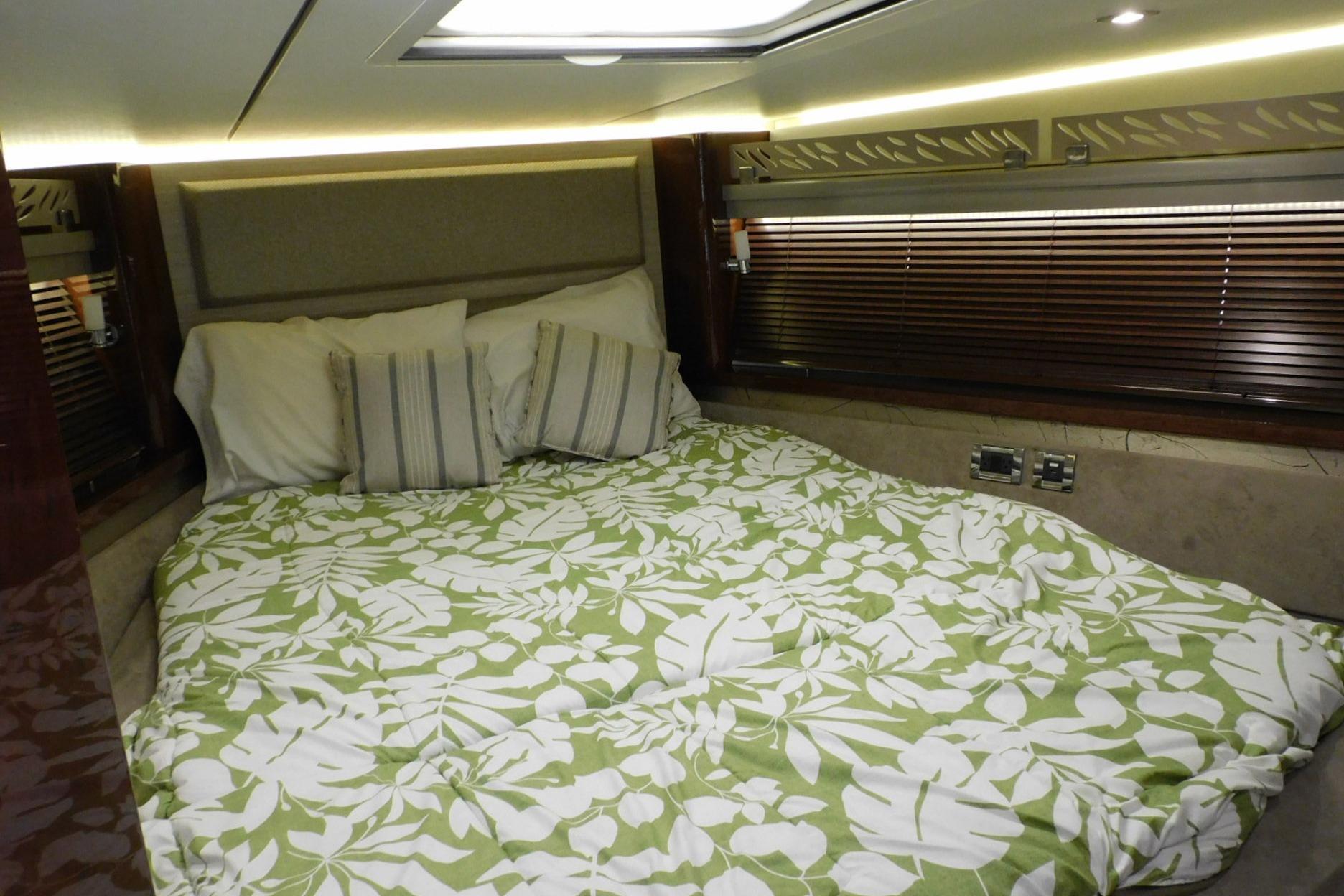Luxurious 2019 Sea Ray L550 yacht bedroom with floral bedding and elegant lighting.